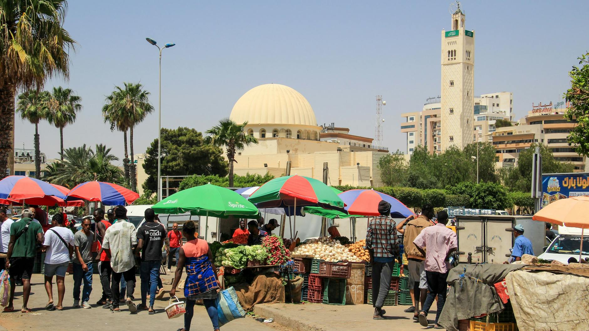 Ausländer aus afrikanischen Staaten südlich der Sahara gehen an einen Gemüsemarkt in Sfax: vorbei.