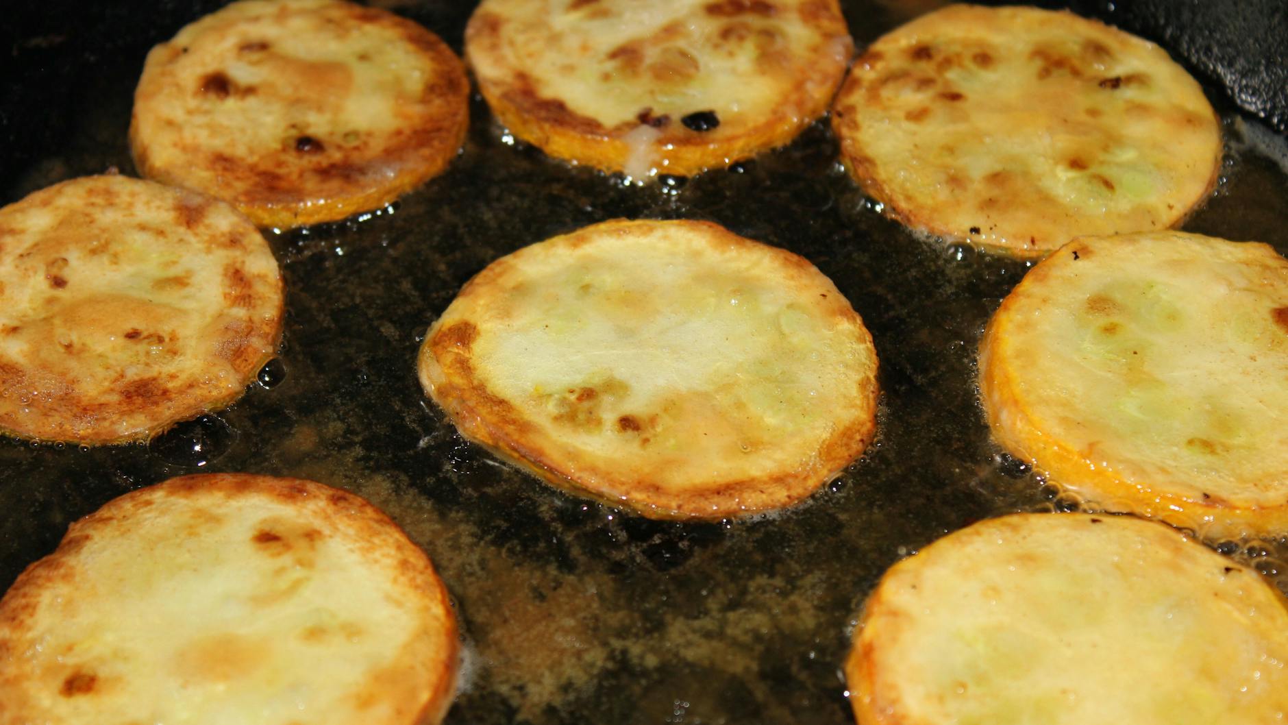 Die Zucchini im Teigmantel werden in der Pfanne frittiert.