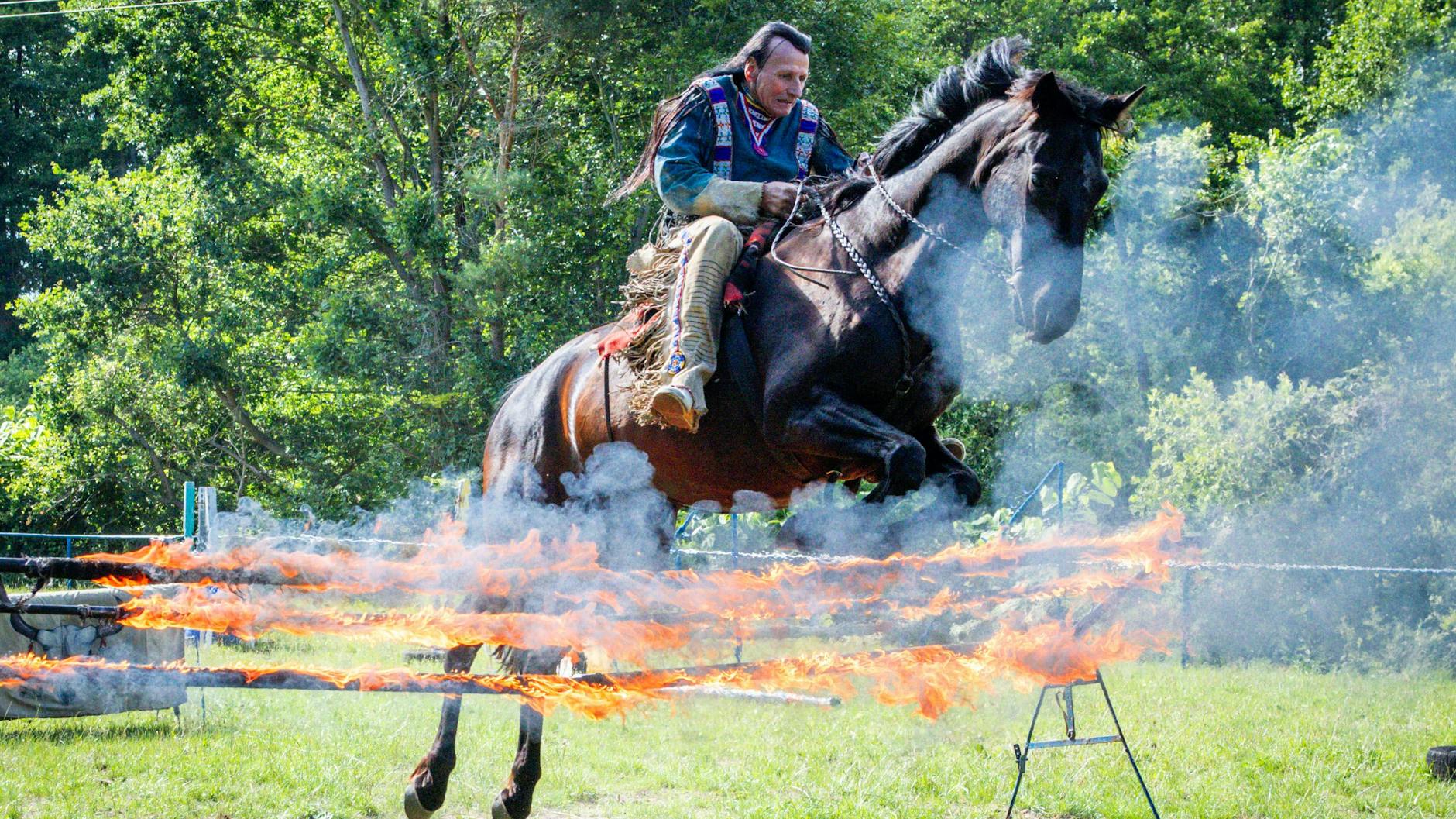 Tollkühner Sprung! DDR-Stuntman Wolfgang Kring springt mit seinem Pferd beim Training für die mittlerweile 30. Apachen-Liveshow über ein brennendes Hindernis.