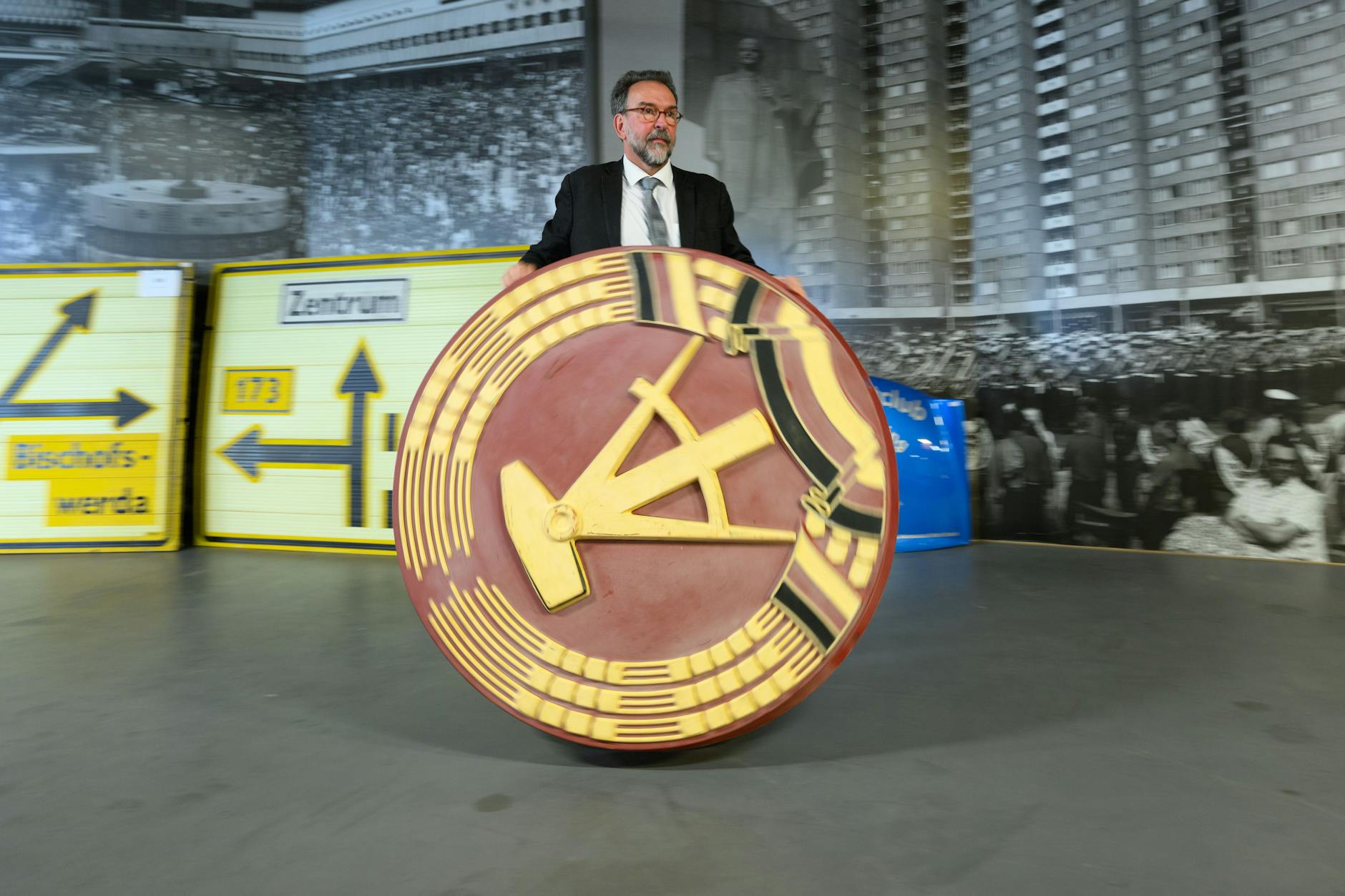 Auktionator Stefan Günther rollt ein 1,20 Meter großes DDR-Emblem durch das DDR-Museum im Simmel-Center am Albertplatz. Nach der Schließung des Museums Die Welt der DDR im April 2023 werden am 8. Juli 2023 die Ausstellungstücke versteigert.