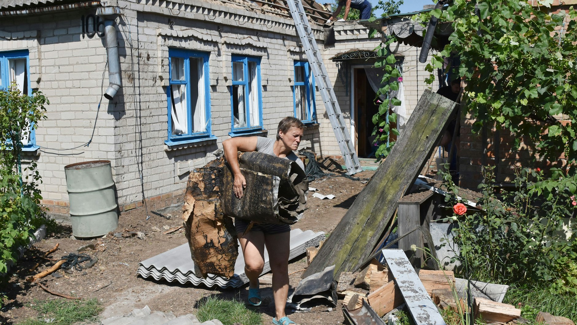 Eine Frau beseitigt die Trümmer eines beschädigten Hauses in Kuschuhum.