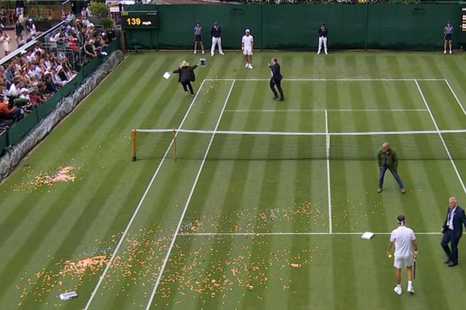 Oranges Konfetti und Puzzleteile schmissen zwei angebliche Klima-Protestler mitten im Match von Dimitrov gegen Shimabukuro auf den Rasen von Wimbledon.