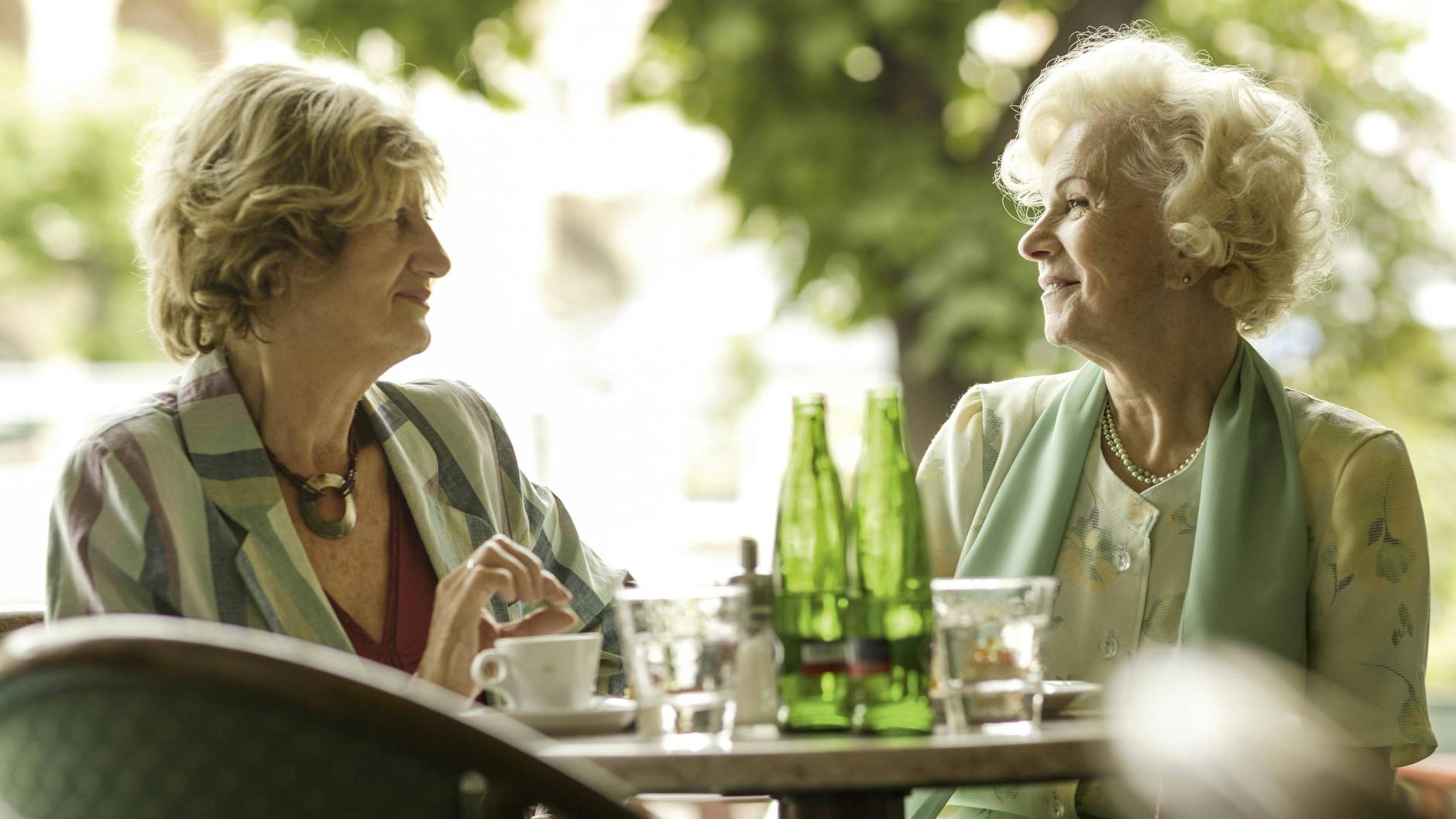 Zwei Seniorinnen sitzen in Straßencafe 
