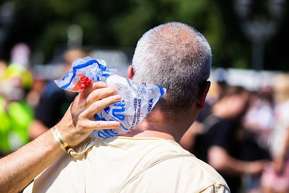 Erste Hilfe gegen Überhitzung: Eine Person hält einer anderen bei der Technoparade „Rave the Planet“ in Berlin einen Eisbeutel in den Nacken.