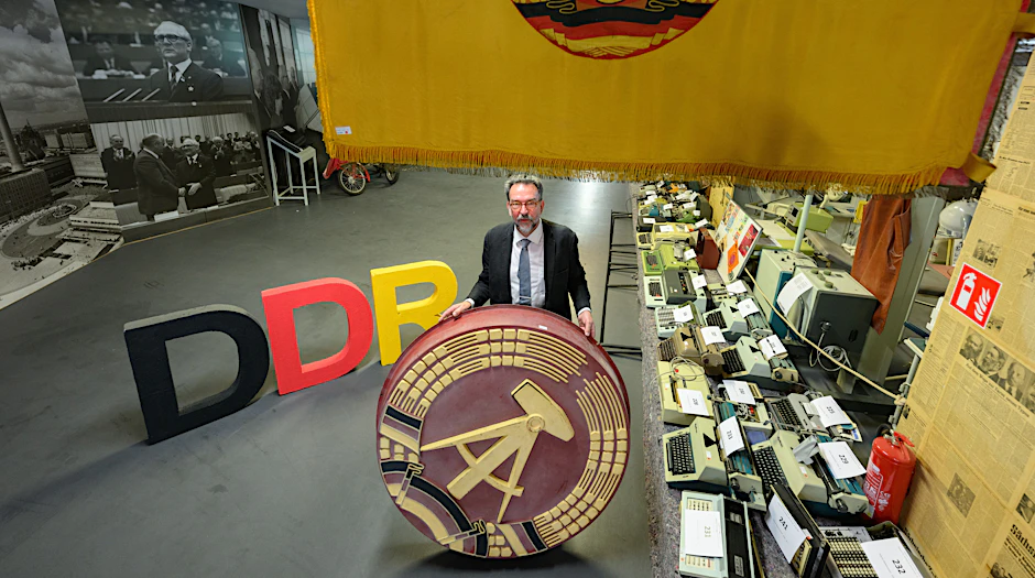 Auktionator Stefan Günther hält ein 1,20 Meter großes DDR-Emblem im DDR-Museum im Simmel Markt am Albertplatz. Nach der Schließung des Museums „Welt der DDR“ im April 2023 werden am 8. Juli 2023 die Ausstellungstücke versteigert.&nbsp;