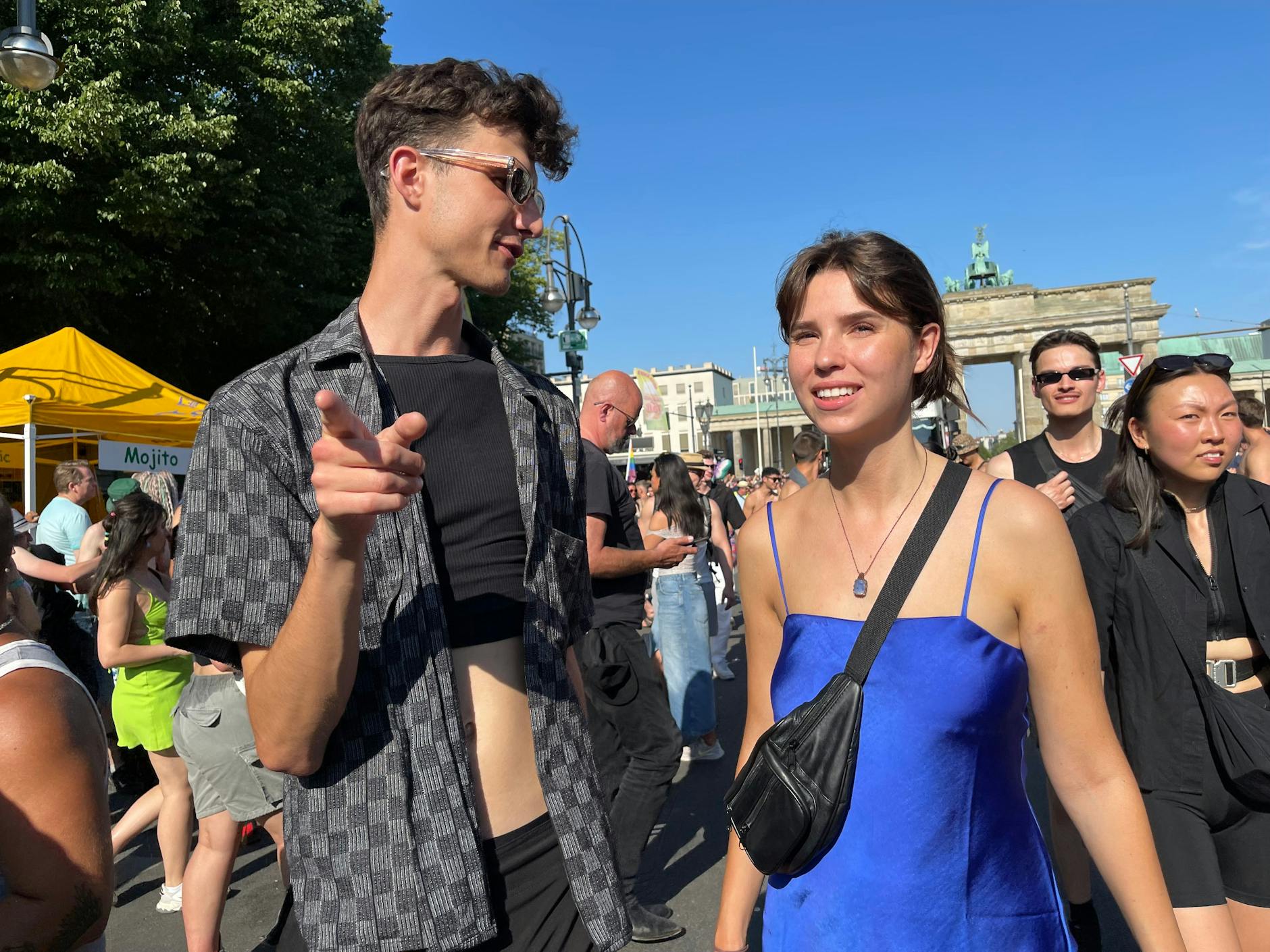 Links ein kariertes Hemd mit Cropped-Top darunter, rechts ein seidig schimmerndes Kleid in Blau