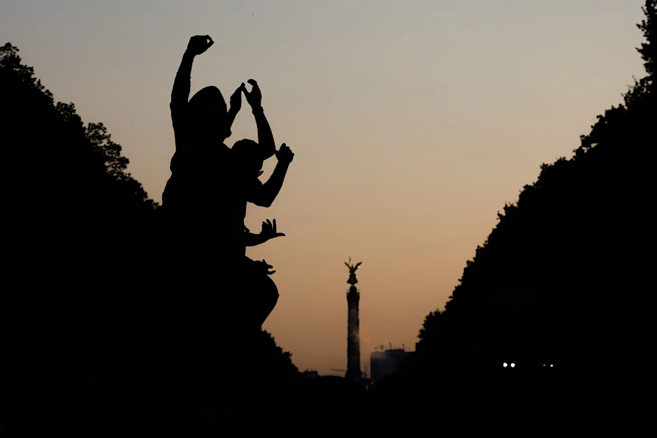 Feiernde tanzen in der Abenddämmerung bei der Technoparade Rave the Planet auf der Straße des 17. Juni vor der Siegessäule.