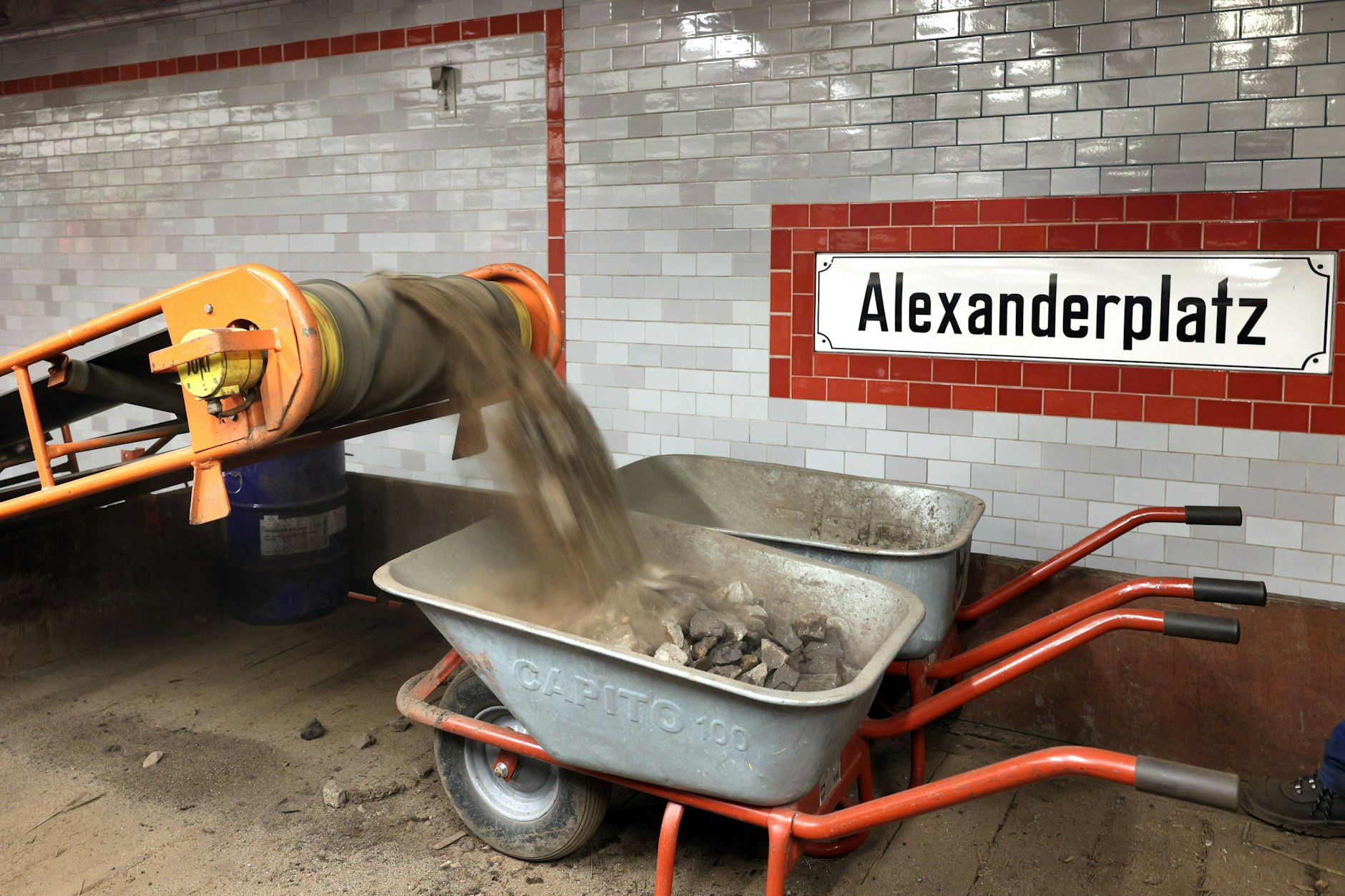 Mit Förderband und Schubkarren wird der Schotter abtransportiert.