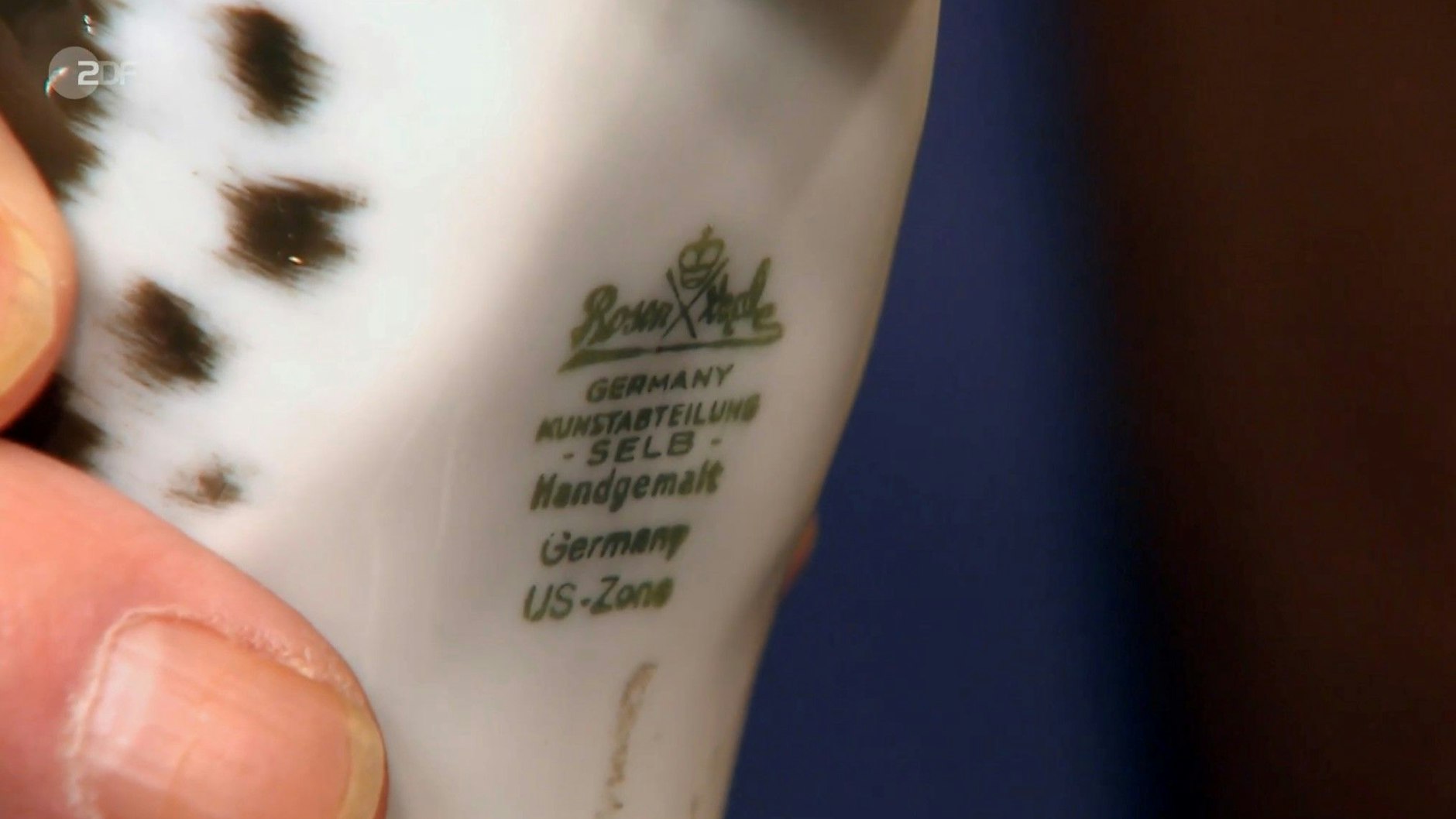 Der „Bares für Rares“-Experte zeigt das Logo: Die Deutsche Dogge wurde bei der Firma Rosenthal hergestellt.