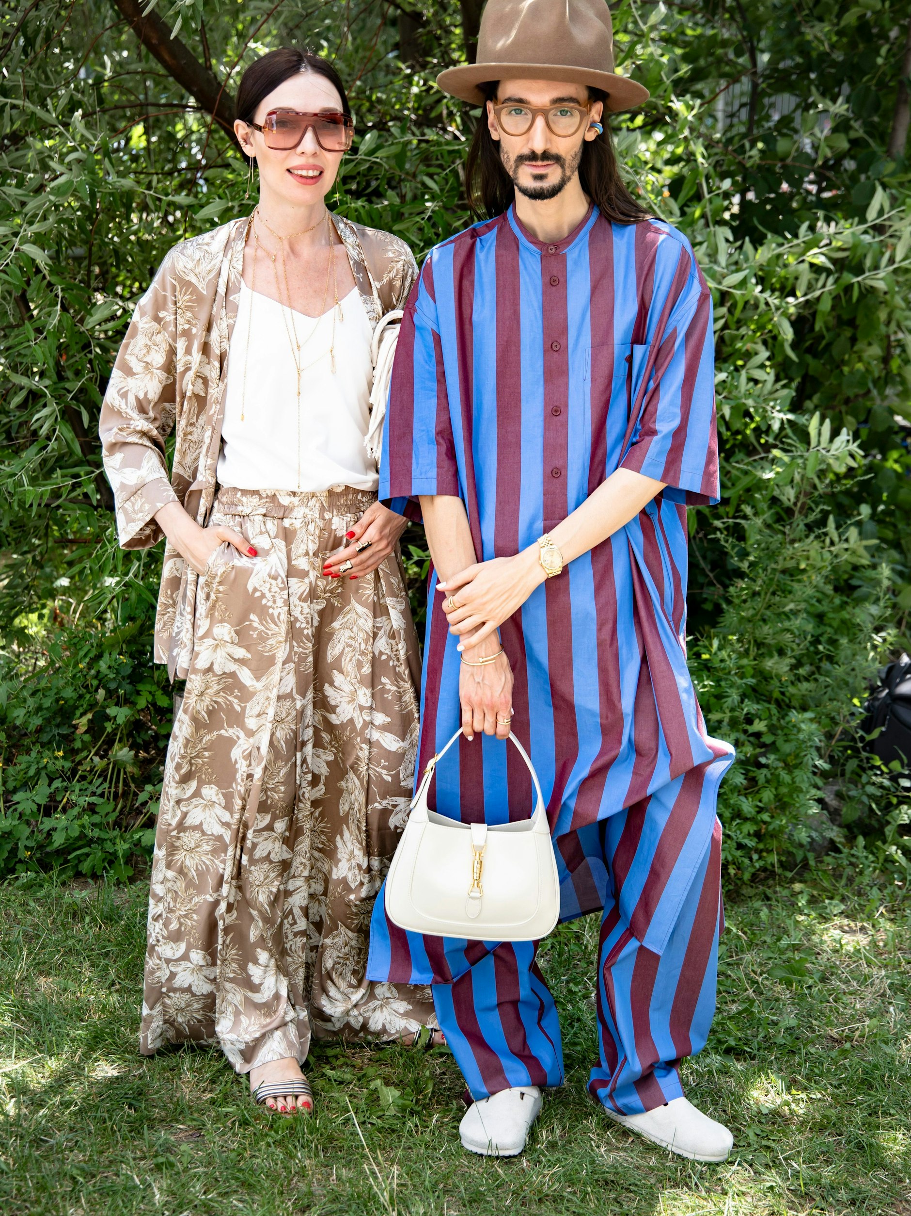 Gegen die Hitze perfekt gewappnet: Der Stylist Julian Daynov und seine Begleiterin tragen luftige Ensembles. Daynov ist ein Darling der Berliner Szene und trägt oft Marken aus Deutschland. An seiner Hand baumelt trotzdem eine Gucci-Tasche.