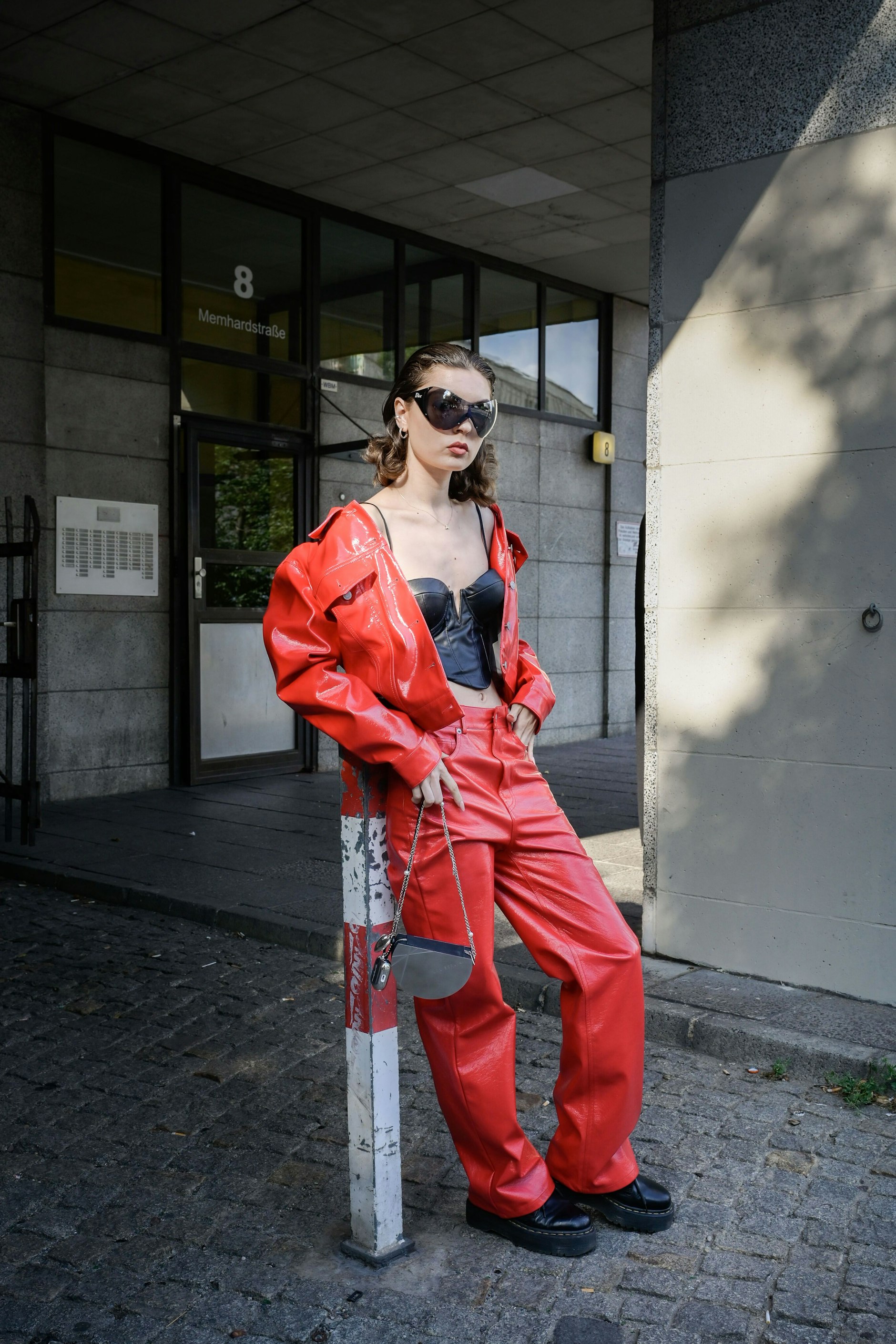 Leicht angeschwitzt: Zur roten Ledermontur kombiniert diese Fashion-Week-Besucherin den Wet-Hair-Look und eine Dior-Sonnenbrille. Ihre Tasche kommt vom Berliner Clubwear-Label MYL, die Plateauschuhe von Dr. Martens.