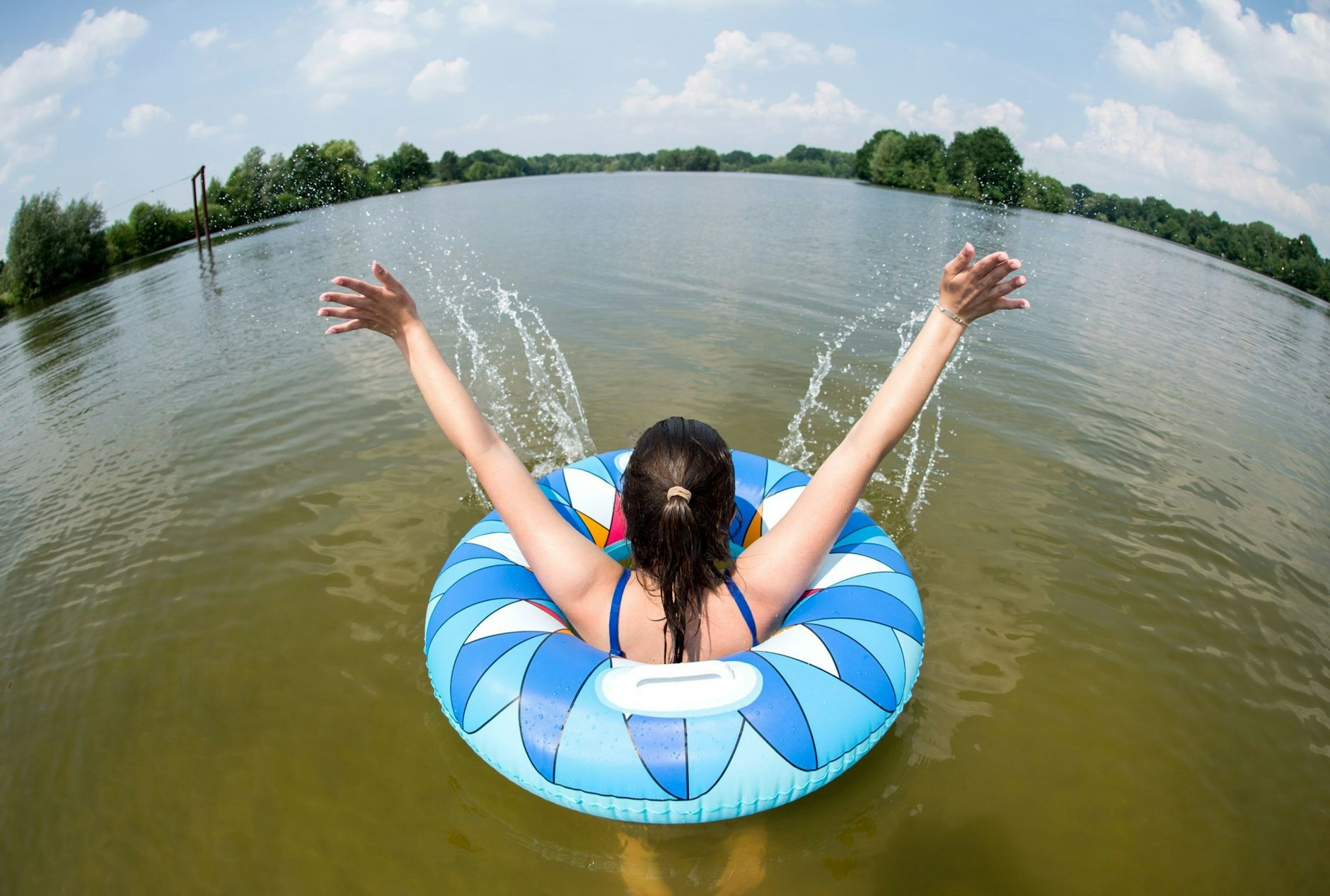 ARCHIV - Eine junge Frau badet mit einem Schwimmreifen in einem See.  bolbild