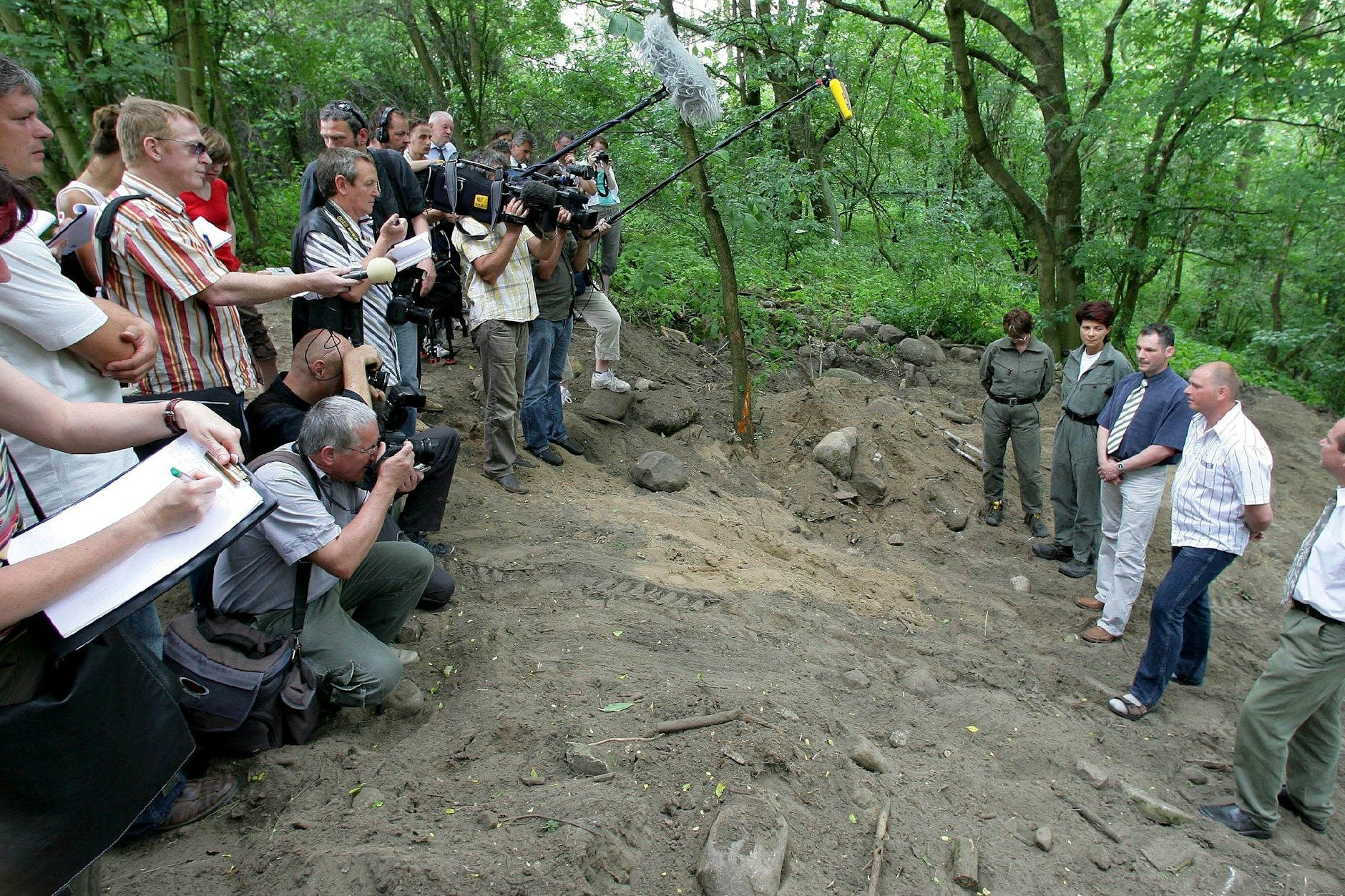 Die Ermittler, darunter auch Michael Halbach (blaues Hemd, Schlips), zeigen Mitte Juni 2006 Journalisten die Stelle in einem Waldstück in Lossow, an der die Leichen gefunden wurden.