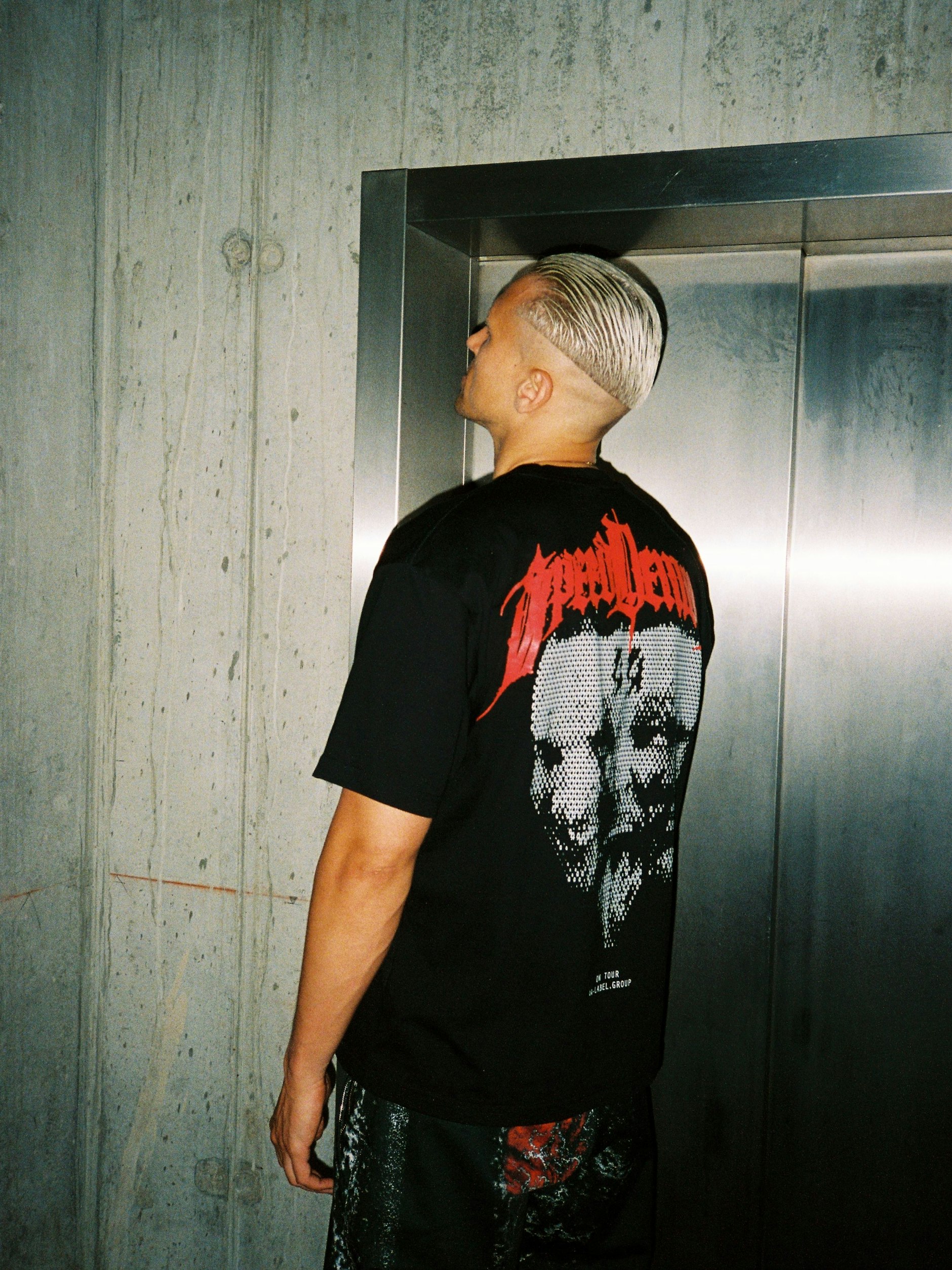 Messerscharf gestylt schlug Szymon alias Somewhen um Mitternacht im Berliner Velodrom auf; direkt nach einem DJ-Gig in Amsterdam. Er ist einer der Top-DJs der R Label Group. Auf der Milan Fashion Week bewies er bei der Show der 44 Label Group zudem kürzlich seine Qualitäten als Model. Das T-Shirt mit seinem Foto auf dem Rücken ist Teil der neuen 44-Kollektion.