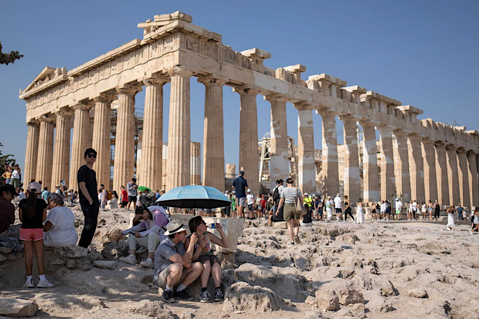 Eine Touristin trinkt Wasser unter einem Sonnenschirm in der Hitze von Athen. Weit über 40 Grad werden am Freitag und Samstag in Griechenland erwartet.