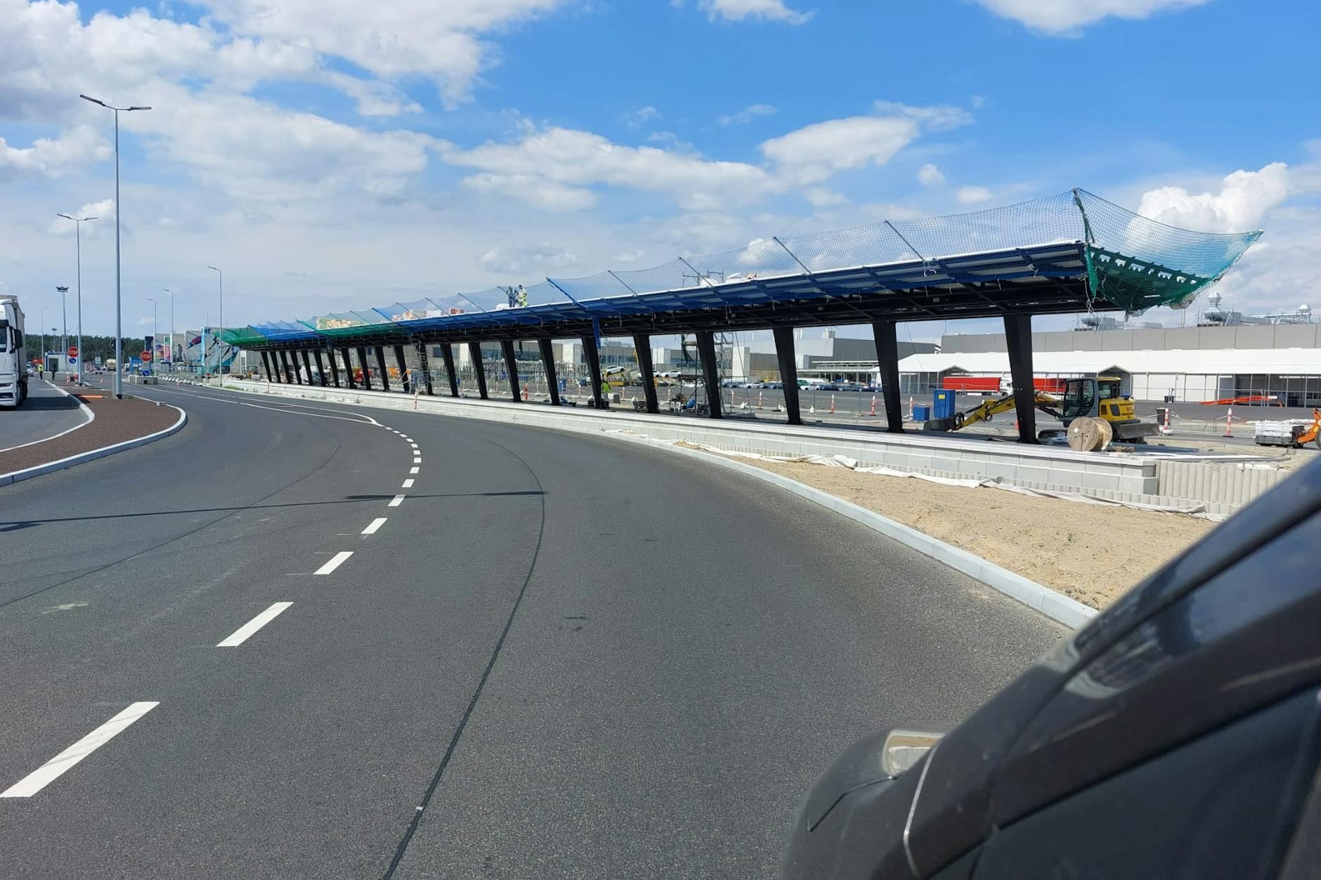 Das ist der neue Bahnhof Tesla Süd. Als das Foto im Juli aufgenommen wird, stehen schon die Dachstützen, und das Dach ist montiert. Nebenan werden Gleise verlegt. Hier sollen die Züge nach Erkner beginnen.