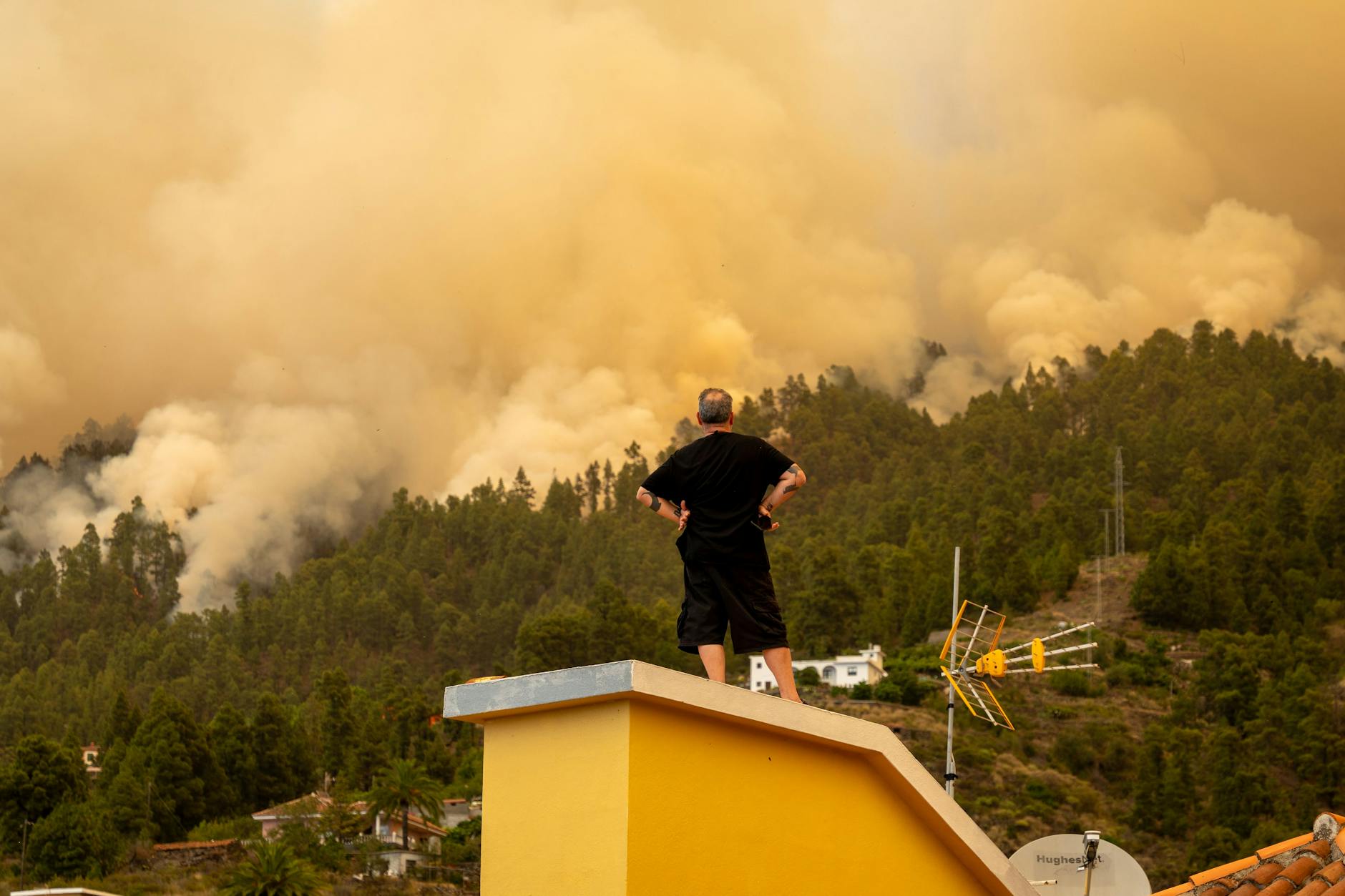 La Palma: Ein Mann beobachtet vom Dach eines Hauses aus den Waldbrand. 