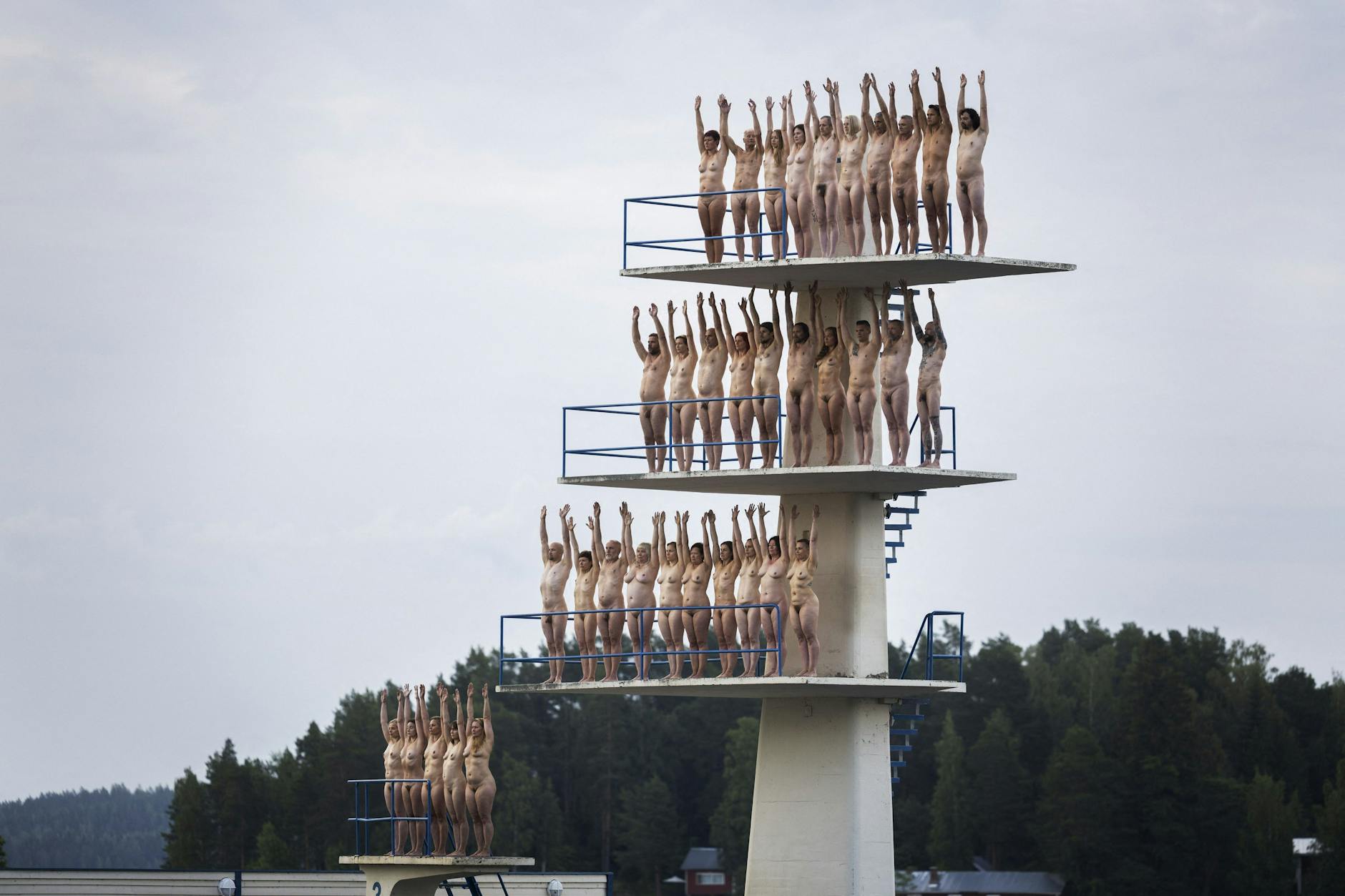 Volunteers stand naked on diving towers on Kuopio Beach. 