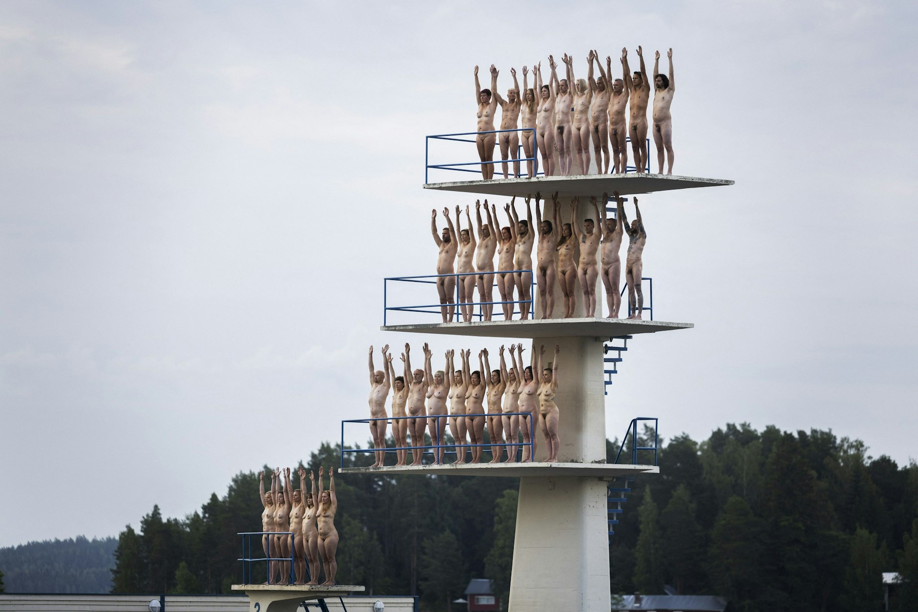 Volunteers stand naked on diving towers on Kuopio Beach.
