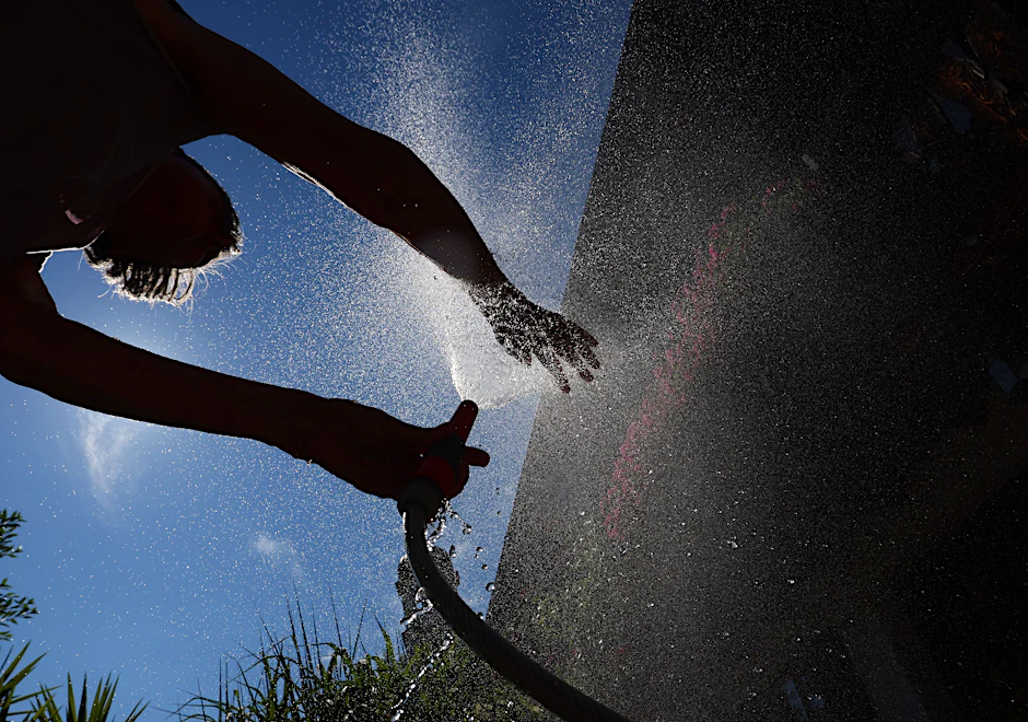 Ein Frau kühlt sich in Bayern mit Wasser aus einem Gartenschlauch ab. Hier wurden 38,8 Grad gemessen.