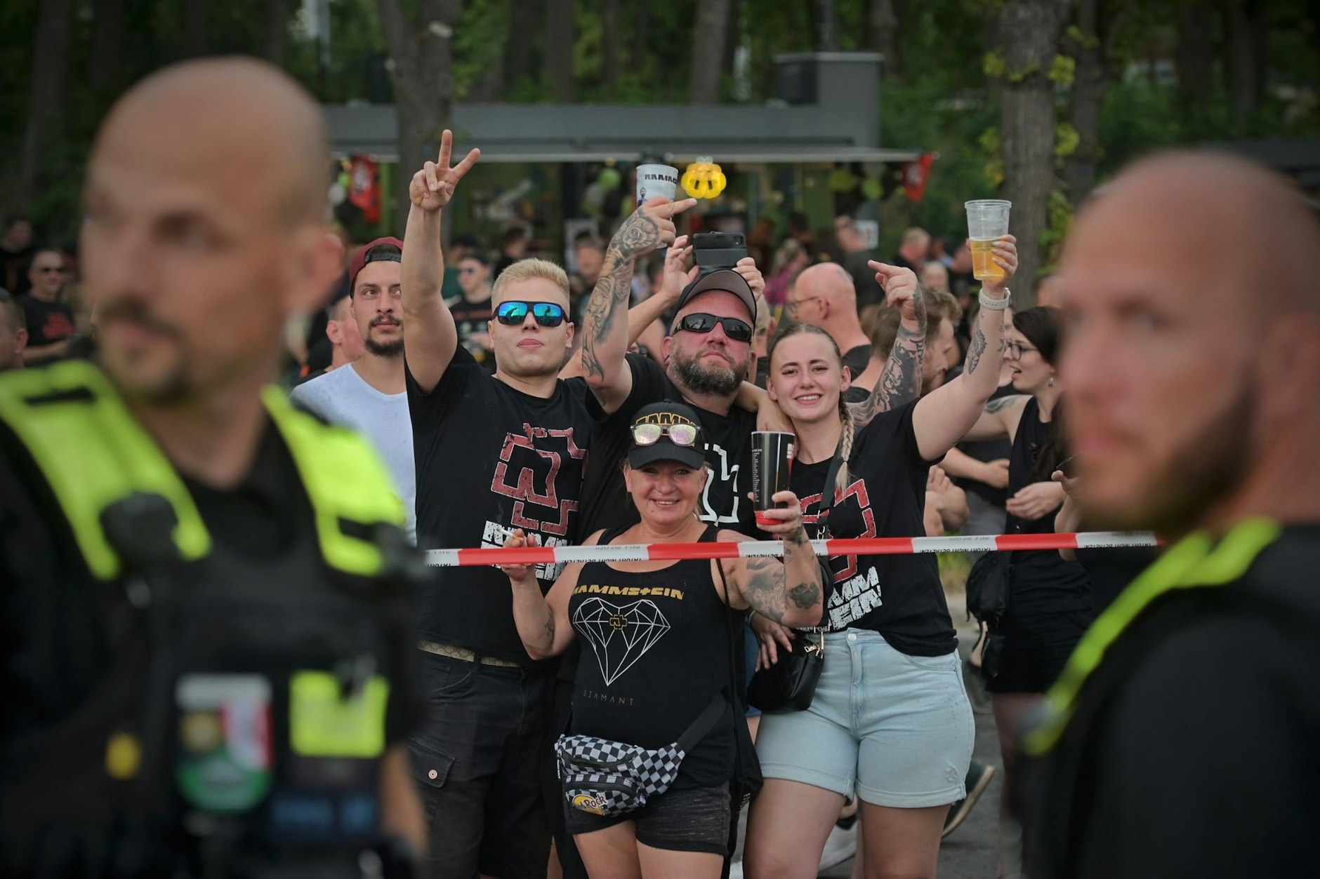 Rammstein-Fans und Demonstranten werden mit Absperrband voneinander getrennt. Es sind immer wieder Mittelfinger zu sehen und Beleidigungen zu hören.