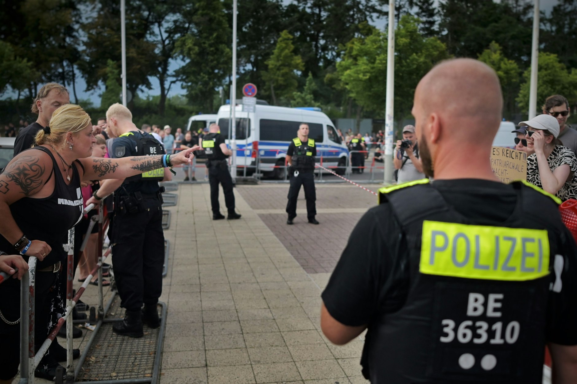 Rammstein-Fans und Demonstranten werden durch Absperrgitter und Polizisten voneinander getrennt.