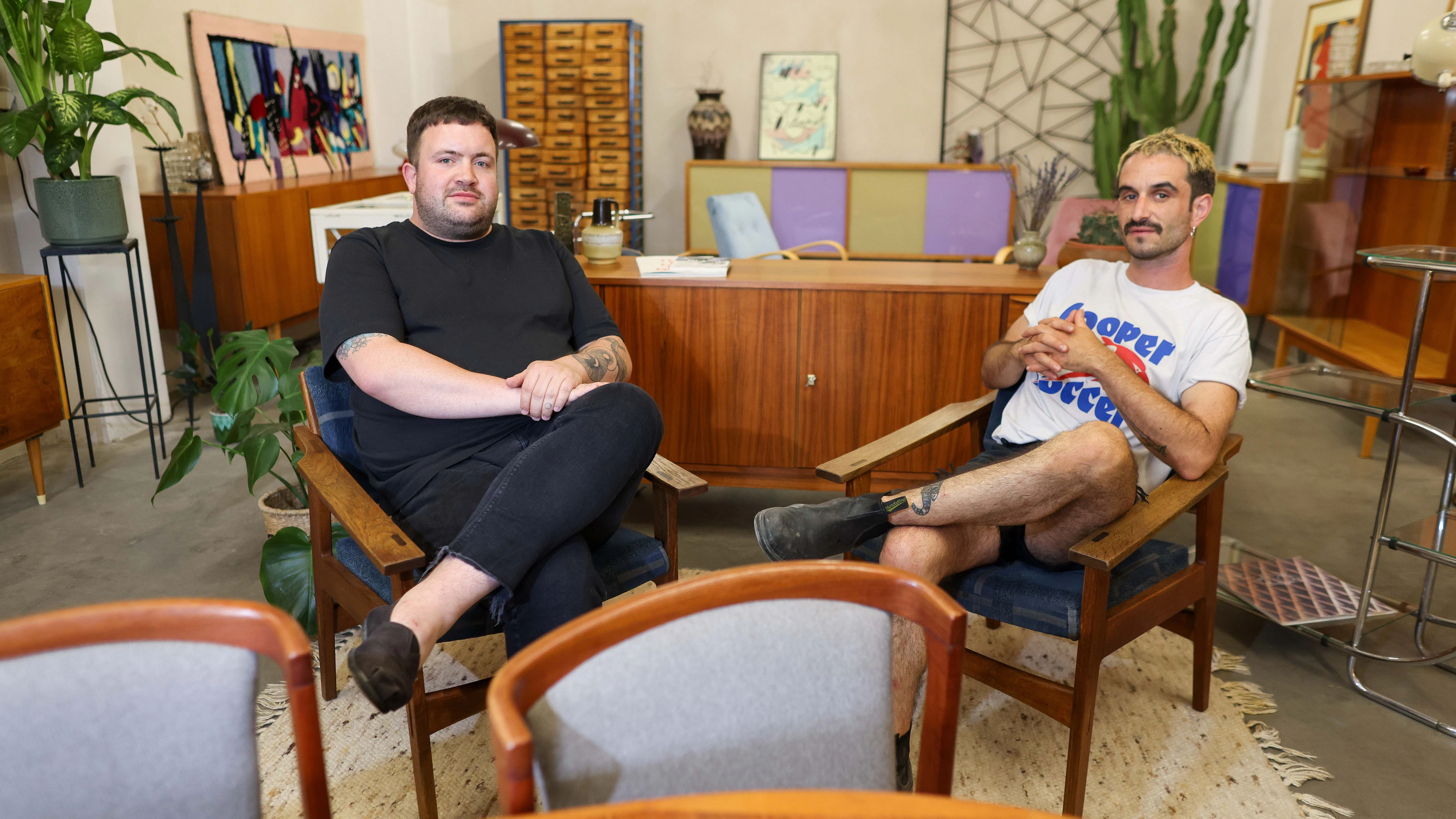 Die beiden Unternehmer Björn Hinrichsen (l) und Kris Sullivan sitzen zwischen von ihnen aufgearbeiteten Möbeln aus den 50er bis 70er Jahren aus der DDR und der ehemaligen Tschechoslowakei. Die hohe Nachfrage nach solchen Möbeln haben sich die Unternehmer zu ihrem Geschäft gemacht.&nbsp;