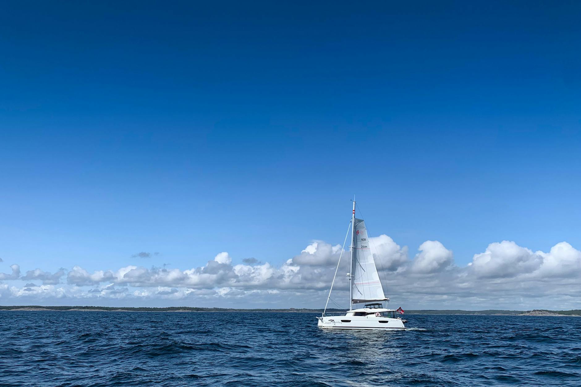 Ein Katamaran fährt bei sonnigem Wetter über die Ostsee.