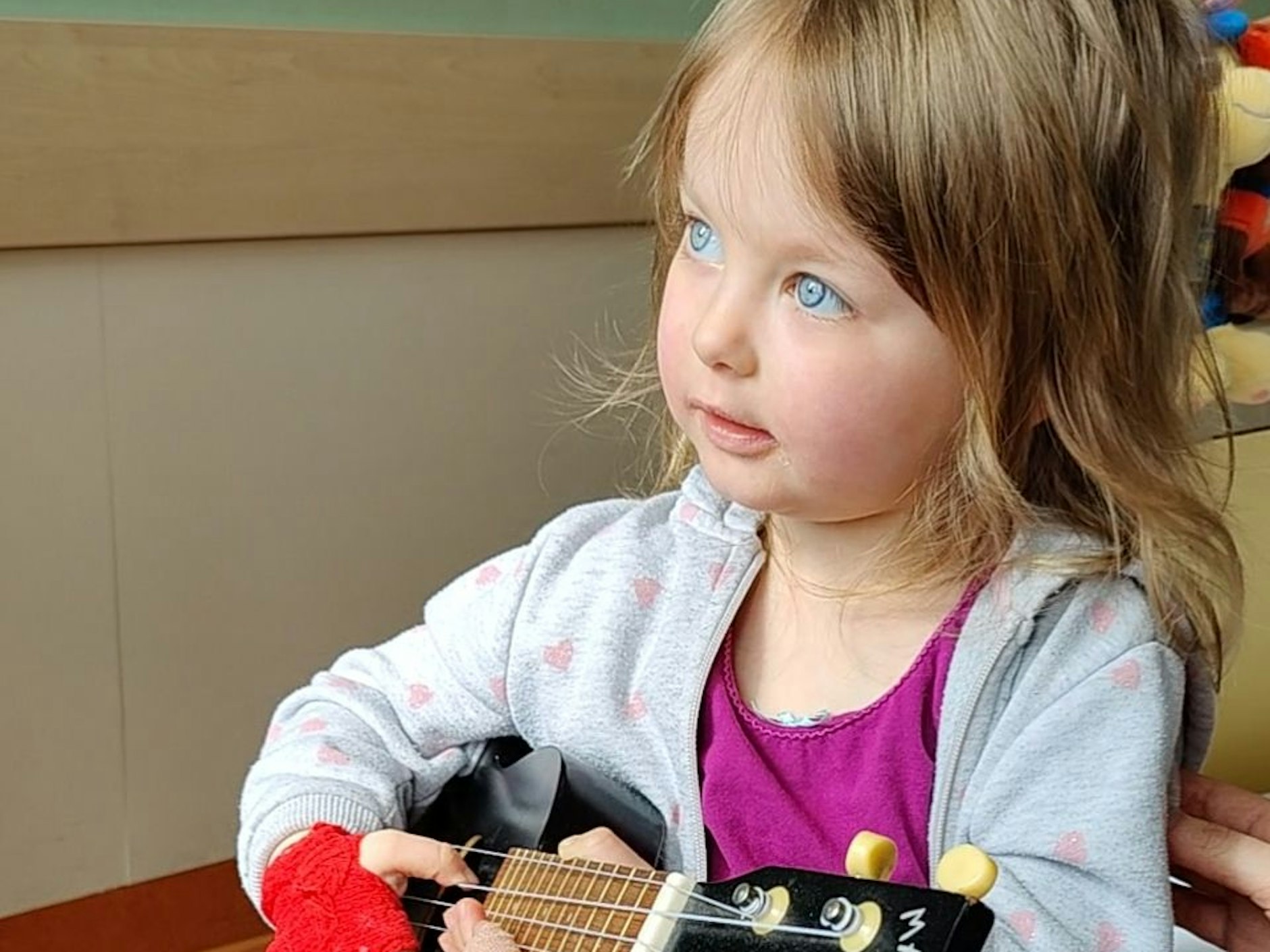 Leandra mit ihrer Spielzeuggitarre. Sie möchte gerne wieder andere Kinder treffen und gesund sein.