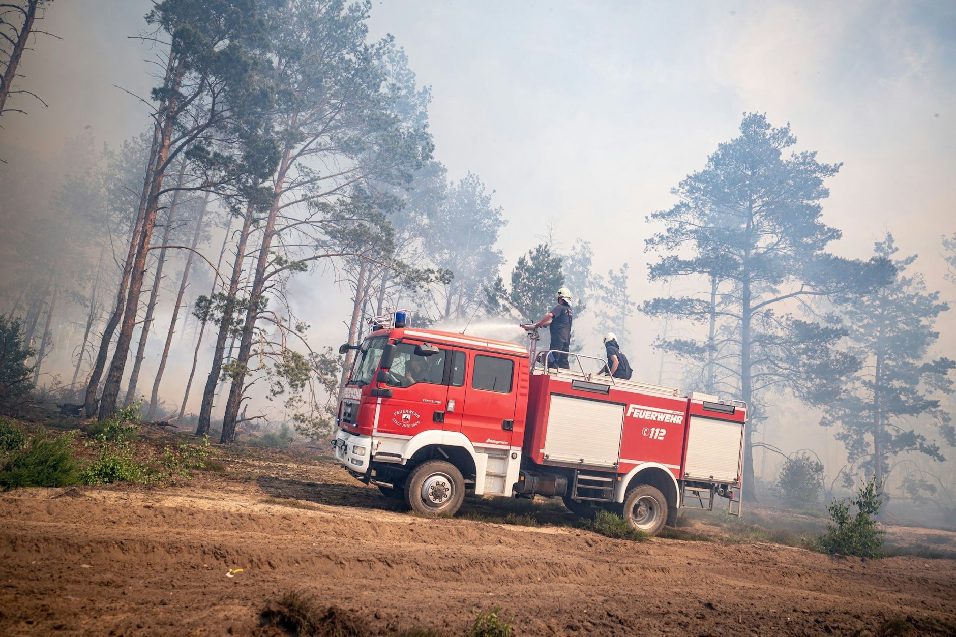 Einsatzkräfte der Feuerwehr bekämpfen in einem Waldstück nahe Jüterbog ein Feuer.