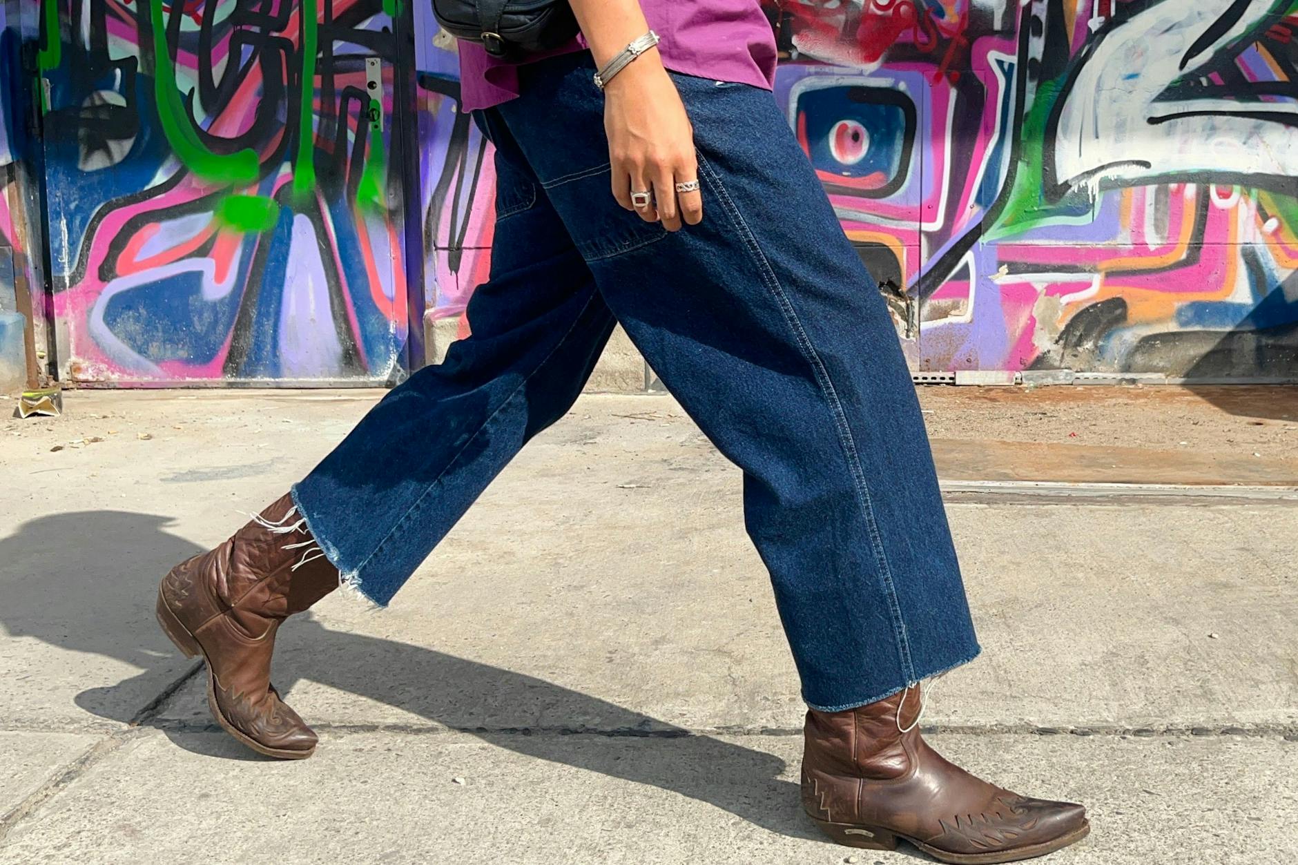 Zeitgemäßer Look bei den Männern: Cowboystiefel und eine weit geschnittene Hose, die wohlgemerkt <em>über</em> dem Schaft getragen wird.
