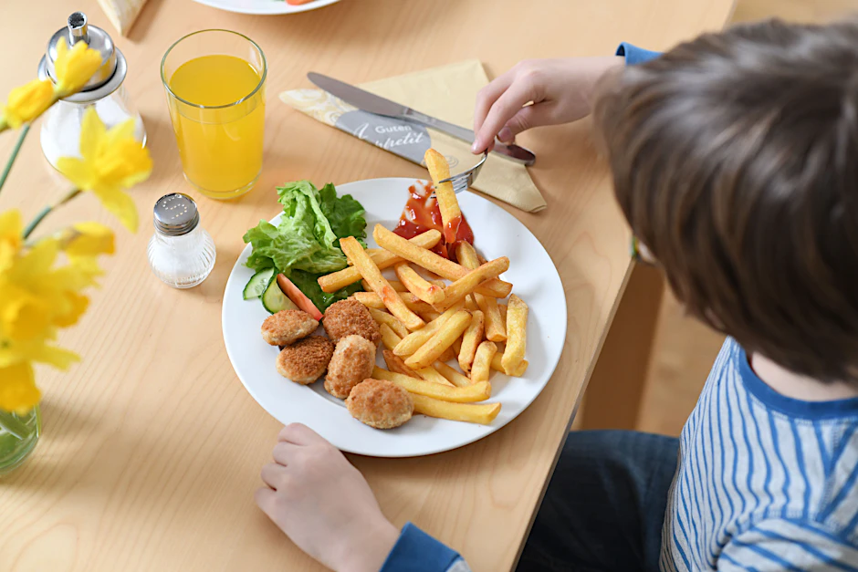 Fast Food: Ein Junge sitzt vor einem Teller mit Chicken Nuggets und Pommes frites (gestellte Szene).
