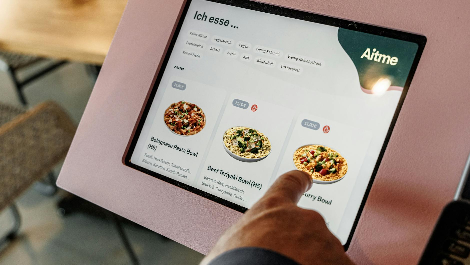 Ein Touchscreen zeigt drei verschiedene Gerichte in Bowls an. Die Zutaten lassen sich individuell verändern.