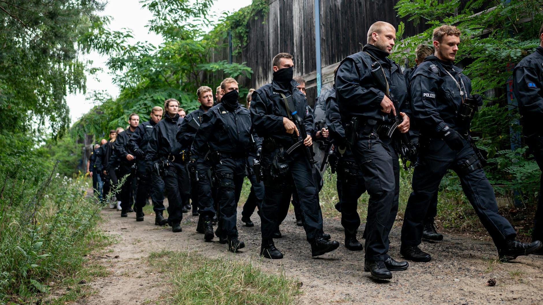 Polizisten laufen im Bereich der südlichen Landesgrenze von Berlin auf der Suche nach einer vermeintlichen Löwin auf einem Waldweg. 