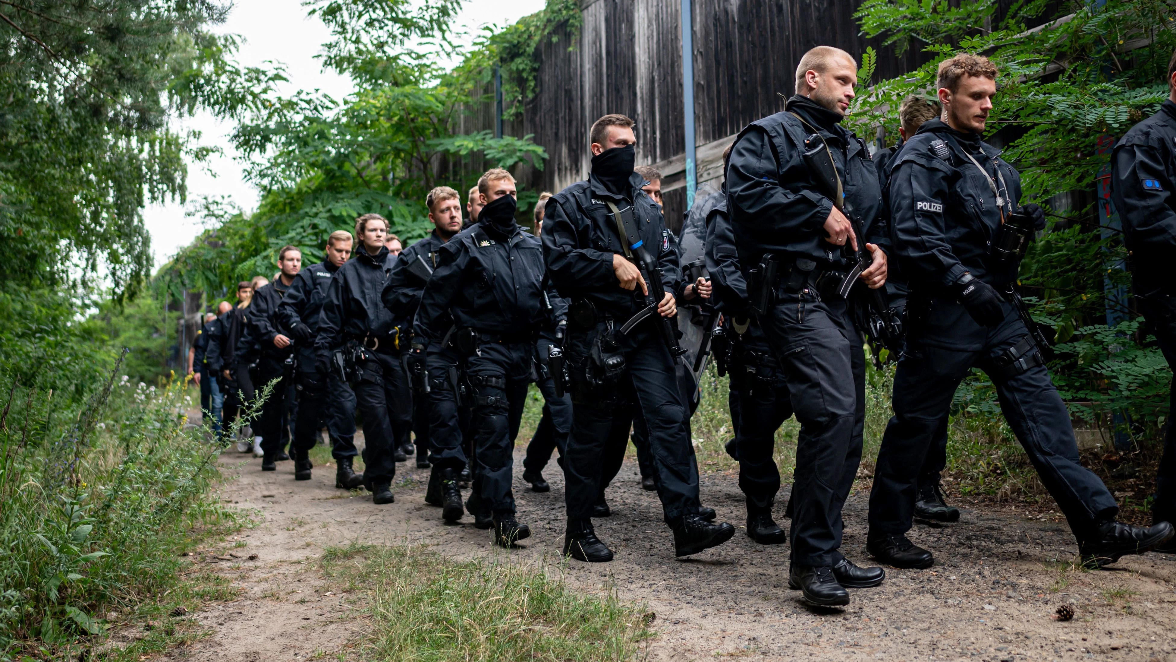 Polizisten laufen im Bereich der südlichen Landesgrenze von Berlin auf der Suche nach einer vermeintlichen Löwin auf einem Waldweg.&nbsp;