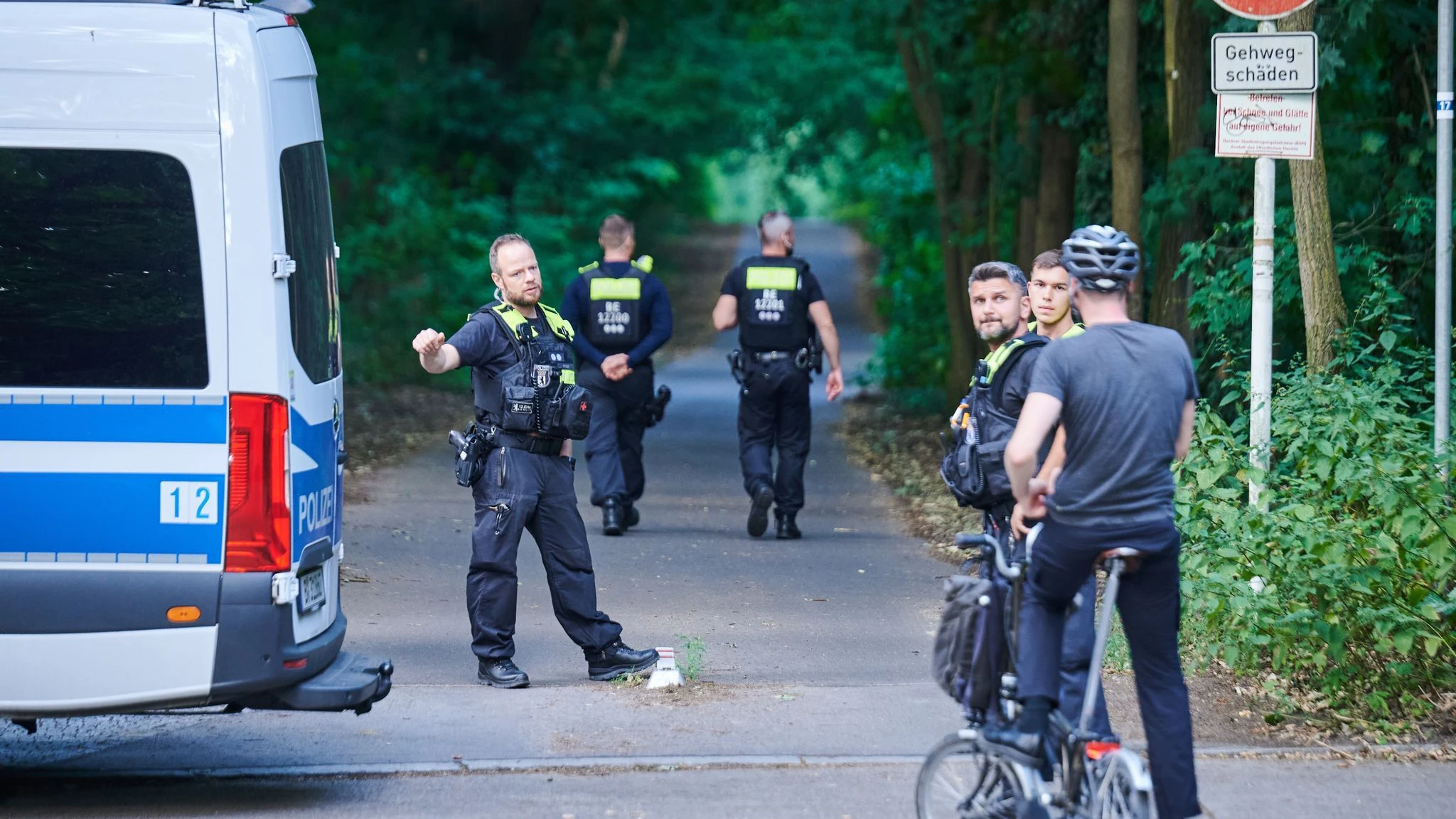 Polizisten stehen am Eingang eines Waldgebietes in dem sich die Löwin befinden soll.