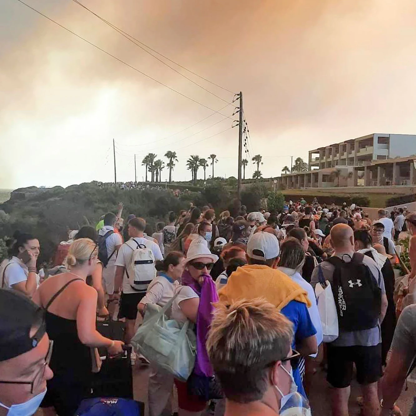 Touristen werden während eines Waldbrandes auf der griechischen Insel Rhodos in Sicherheit gebracht. Viele müssen zu Fuß gehen,