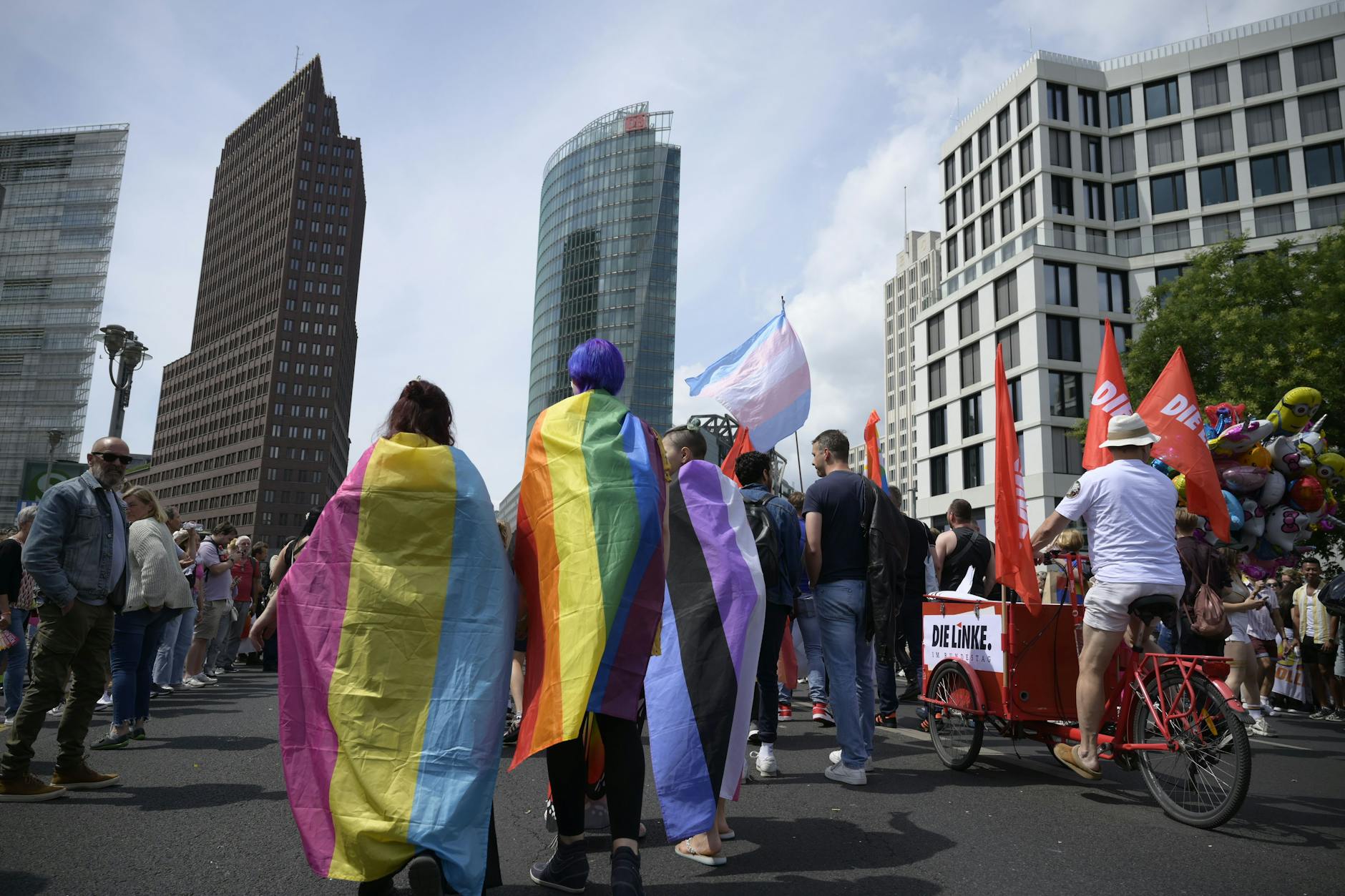 Teilnehmer des CSD-Demonstrationszuges am Potsdamer Platz mit Pansexueller Flagge, Regenbogenflagge und Genderfluid-Flagge.
