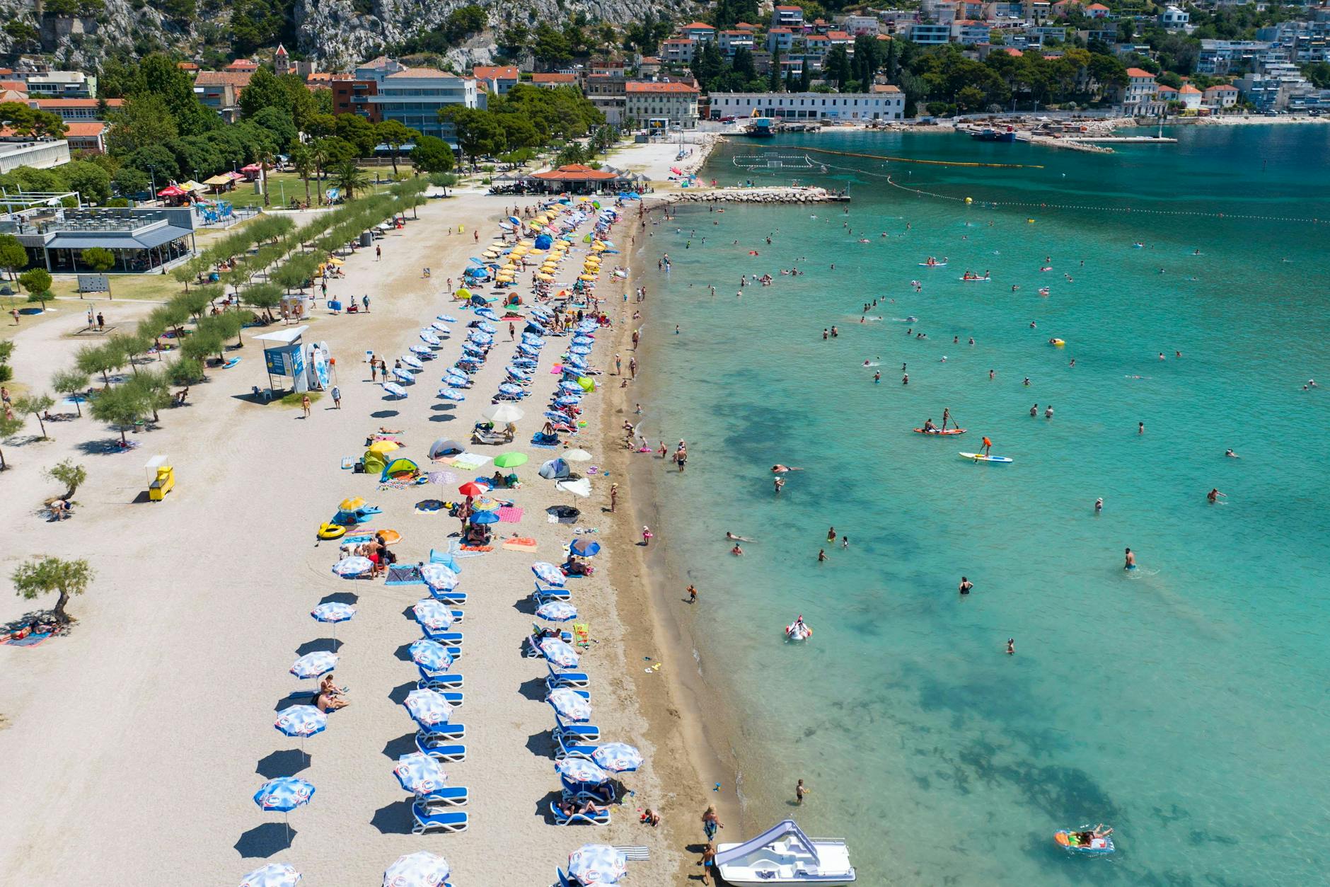Einwohner und Touristen von Omis suchten an dem großen Strand von Omis Erfrischung im Meer.