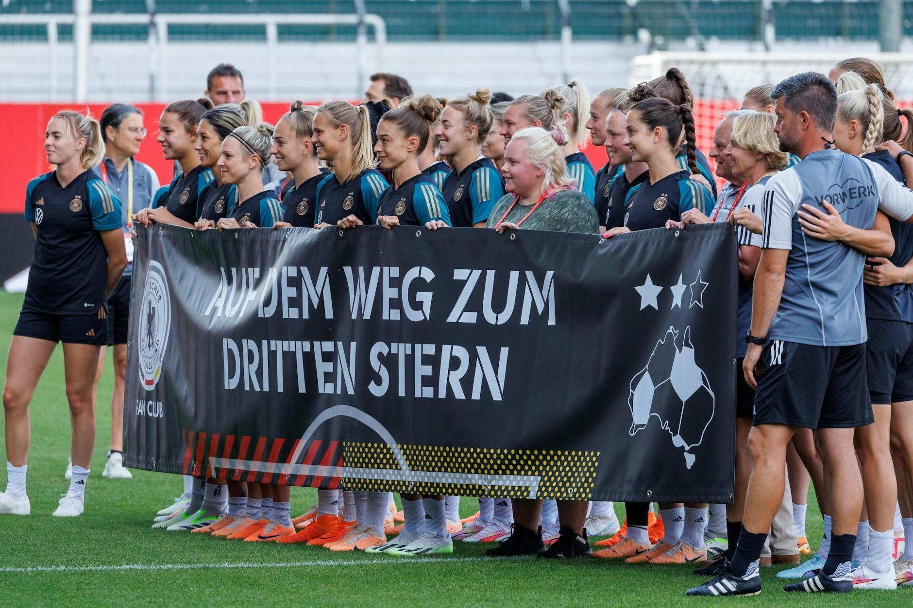 ARCHIV - Die deutschen Spielerinnen stehen beim Abschlusstraining mit einem Banner für ein Gruppenfoto auf dem Platz.