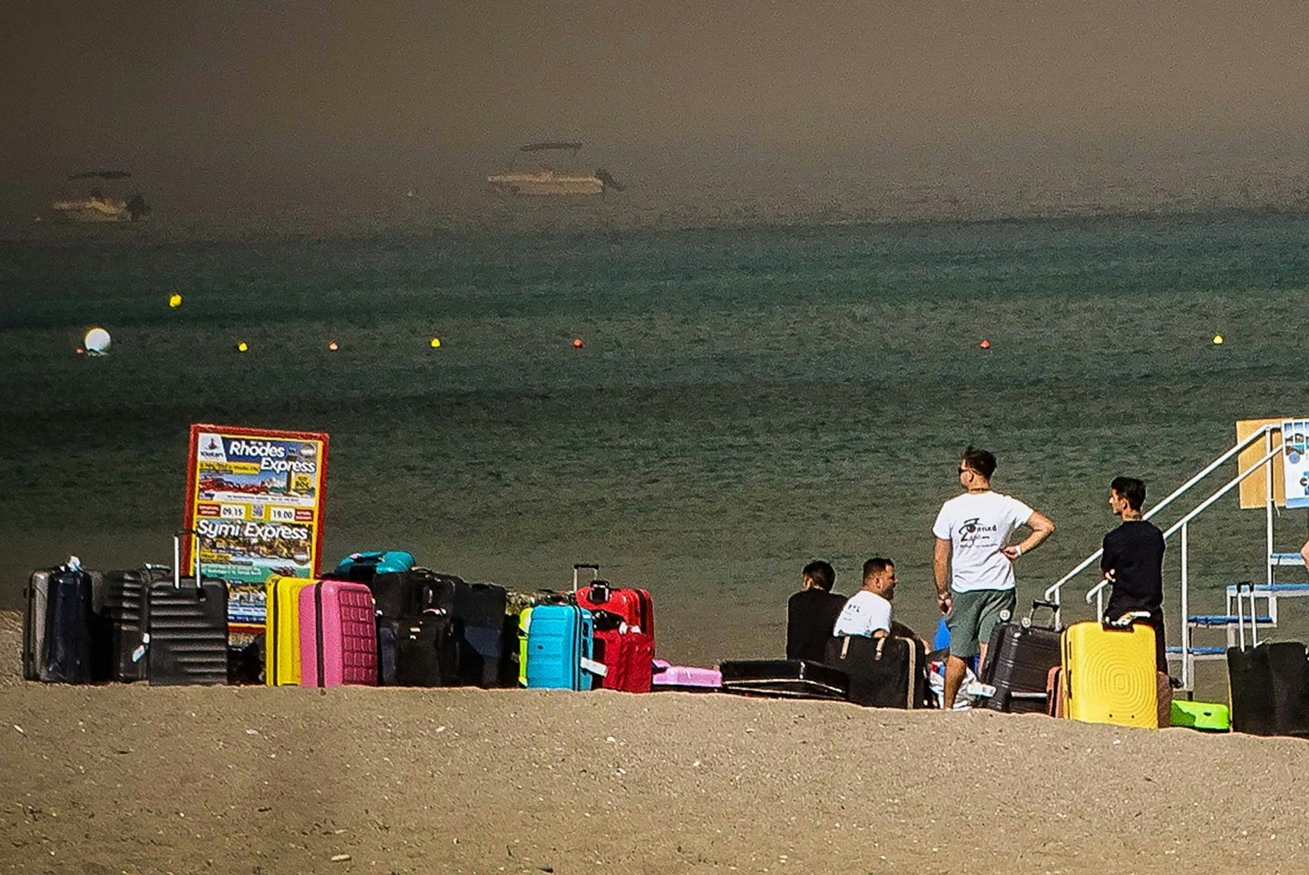 dpatopbilder - Menschen warten darauf, vor den katastrophalen Waldbränden in Sicherheit gebracht zu werden.