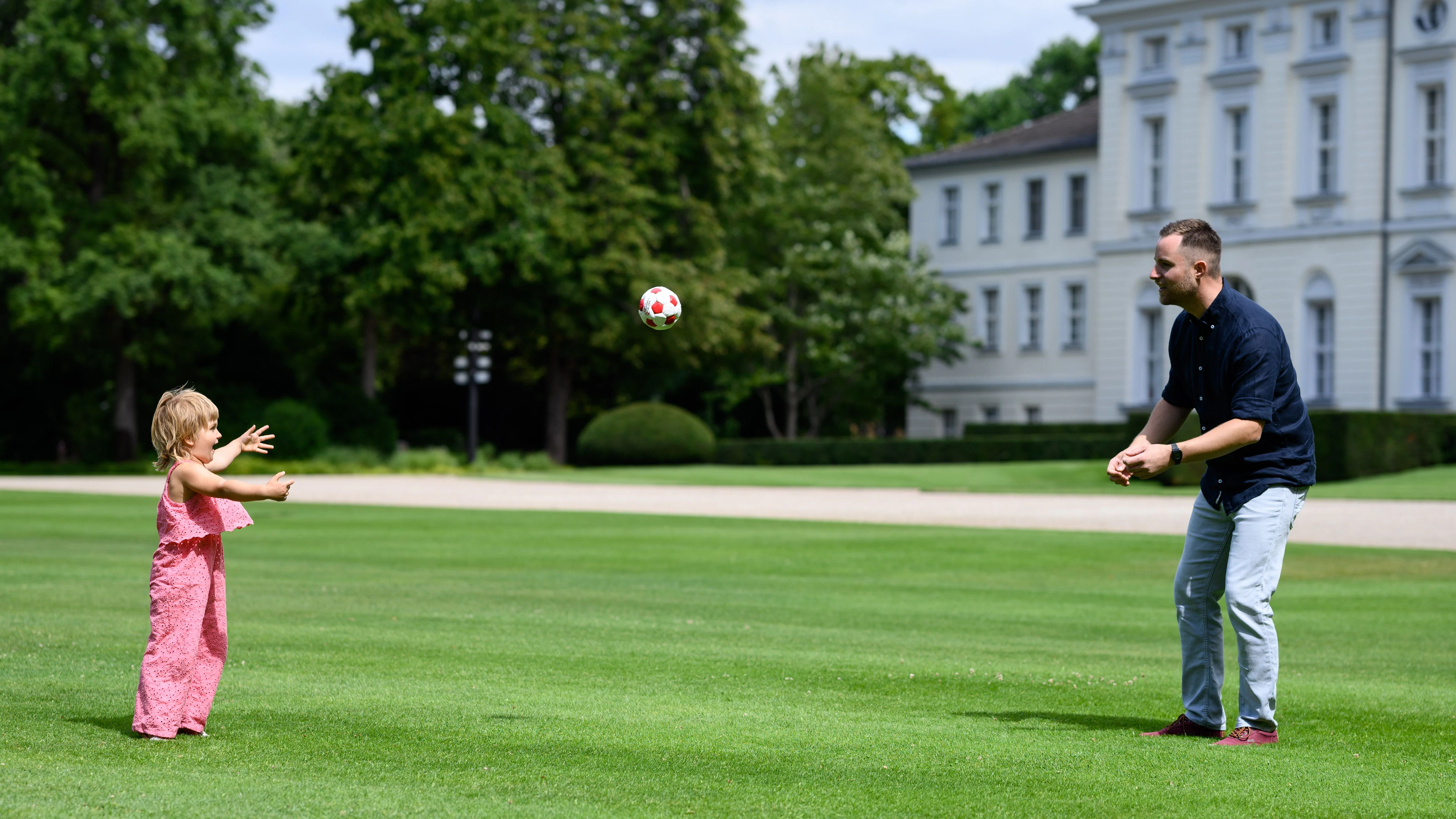 Die kleine Annabel und Fabian Dancker spielen im Park von Schloss Bellevue in Berlin mit einem Ball. Das Mädchen wirkt überglücklich.