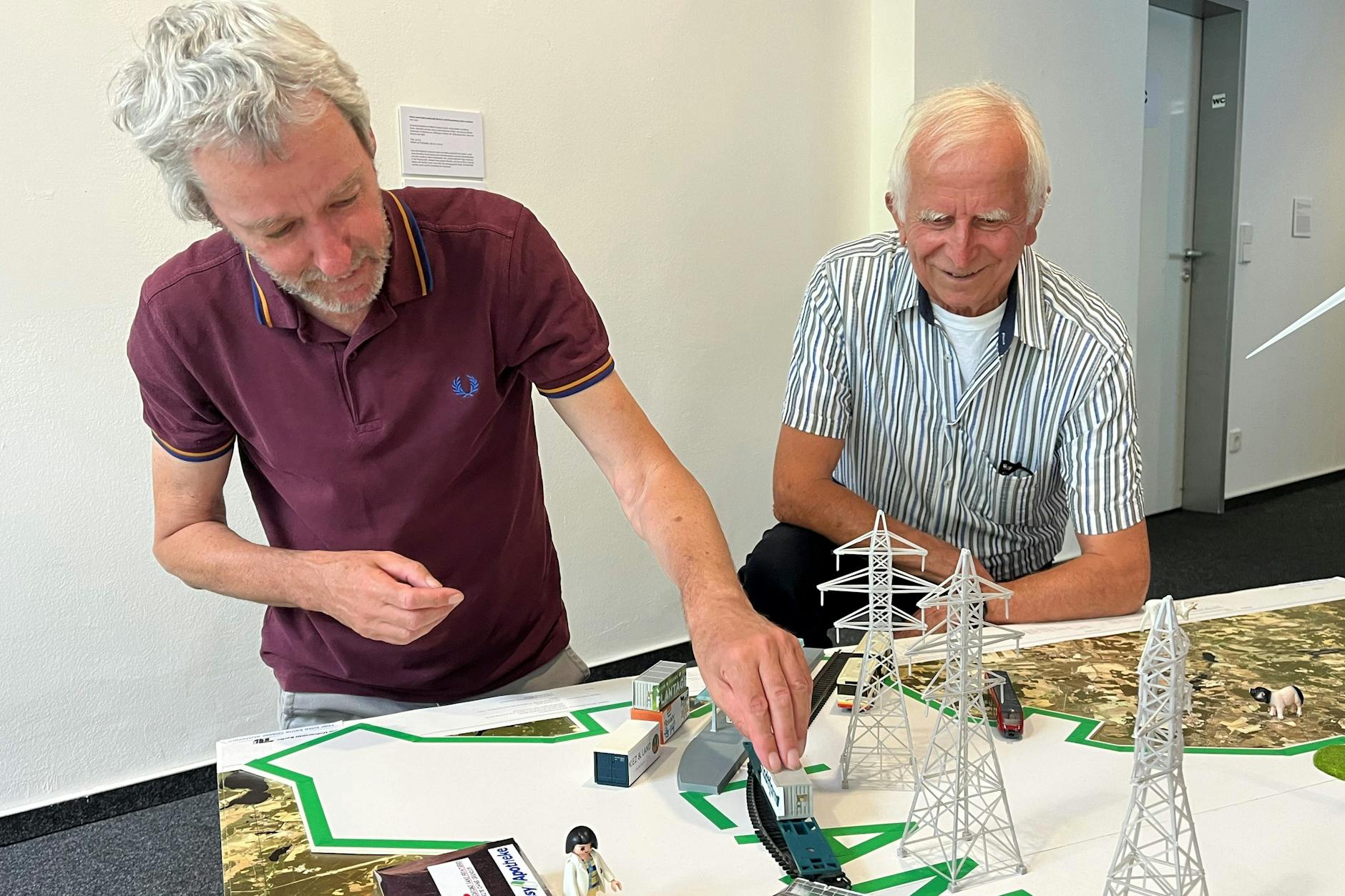 Eine Utopie in Form einer Modelleisenbahn: Adam Page (l.) und Wolfgang Richter mit einem Exponat der Ausstellung „The Last Mile“ im SPD-Haus in Wedding
