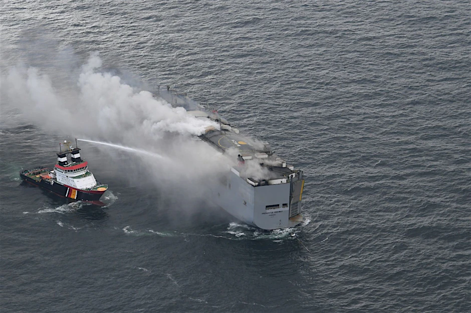 Der brennende Frachter „Fremantle Highway“ in der Nordsee. Links im Bild ist der deutsche Notschlepper „Nordic“ zu sehen, der das Feuer auf dem Frachter bekämpft.