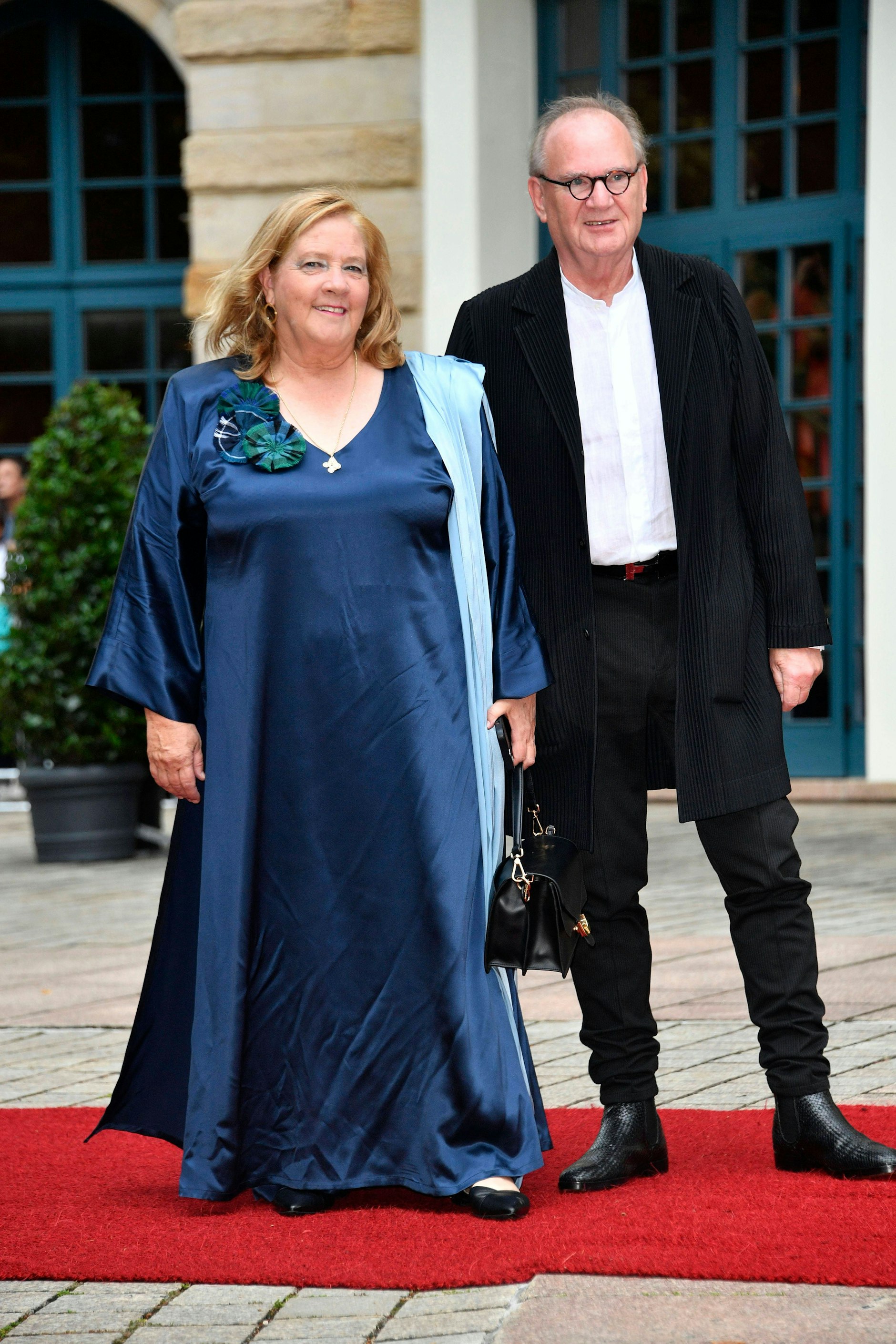 <strong>FLOP:</strong> Unsere Empfehlung: Das Modell „STH2000/20“ von Philips für 44,99 Euro. Für <strong>Kathy Kelly</strong> wäre das wirklich gut investiertes Geld gewesen – schließlich hätte sie so ein praktischer Steamer vor dem faltenreichen Auftritt bei der Festspiel-Eröffnung bewahrt. Die Tochter des Kelly-Family-Clans verfügt aber offenbar nicht über ein solches handliches Dampfgerät, oder sie will es schlichtweg nicht benutzen; auf ihrer mitternachtsblauen Seidensatin-Robe zeichnen sich unschöne Fältchen ab. Das ist besonders ungünstig, weil auch das Kleid an sich in seiner laissez-fairen Weite und mit den unmöglich geschnittenen Flatterärmeln wie ein zerwühltes Nachthemd aussieht. Auch schwierig: die schwarze Henkeltasche im Format eines Arztkoffers.