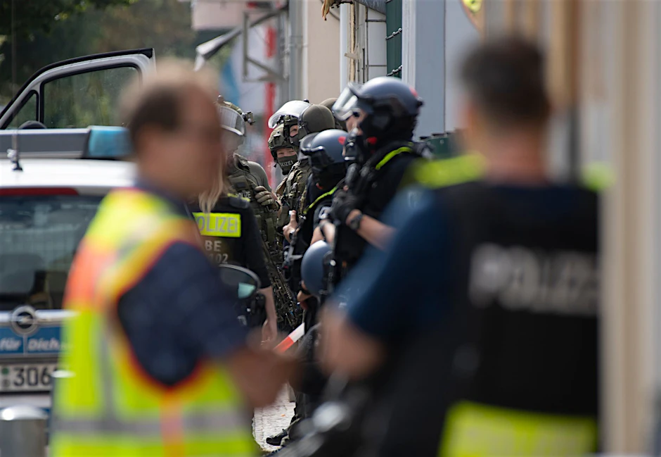 Bewaffnete Polizeikräfte stehen unweit eines Hauses am Brunsbütteler Damm.  