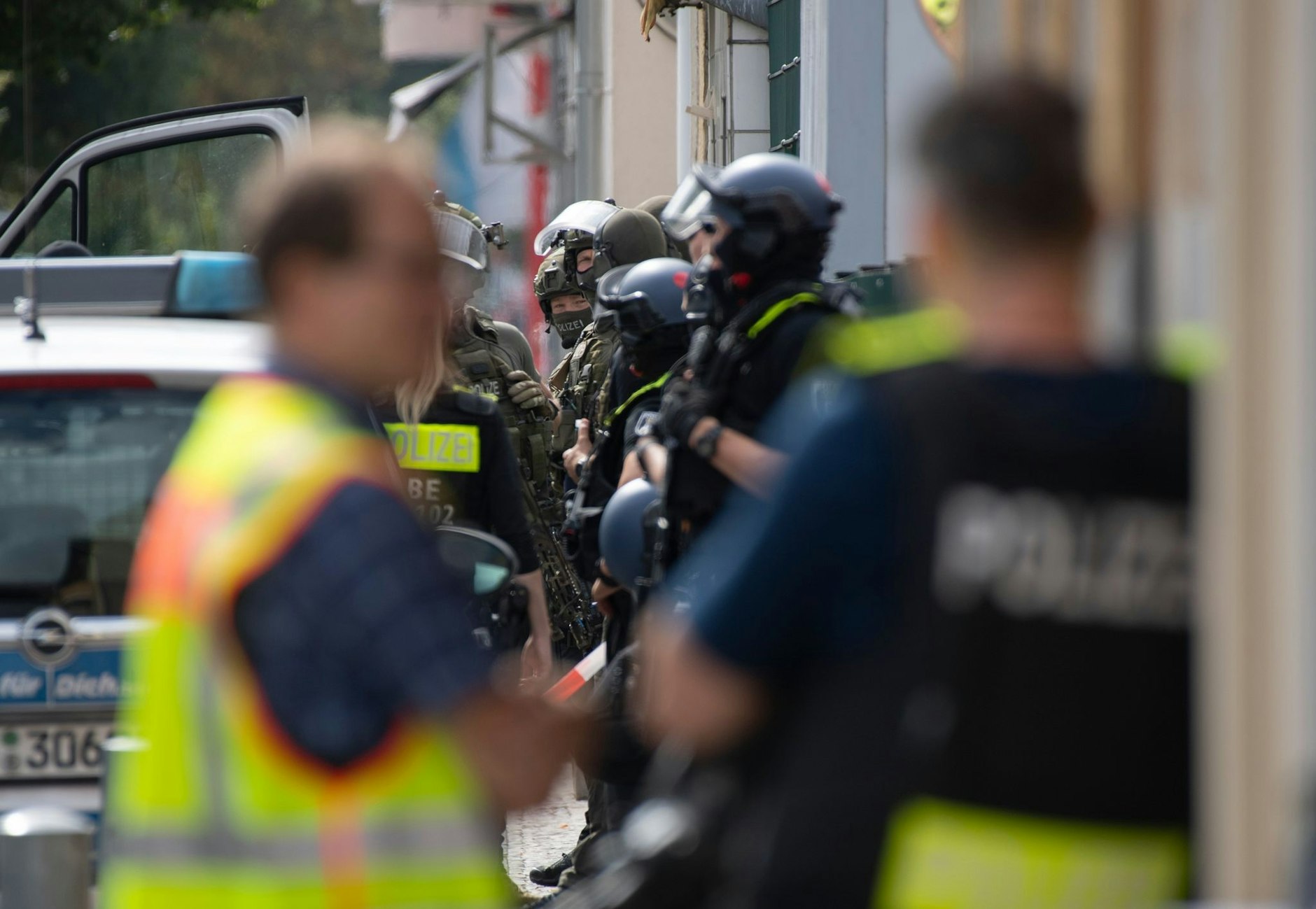 Bewaffnete Polizeikräfte stehen unweit eines Hauses am Brunsbütteler Damm.