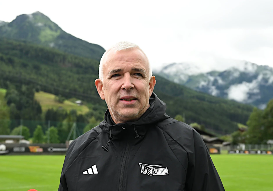Unions Präsident Dirk Zingler steht im Trainingslager vor der Bergkulisse und macht sich so seine Gedanken über das liebe Geld.