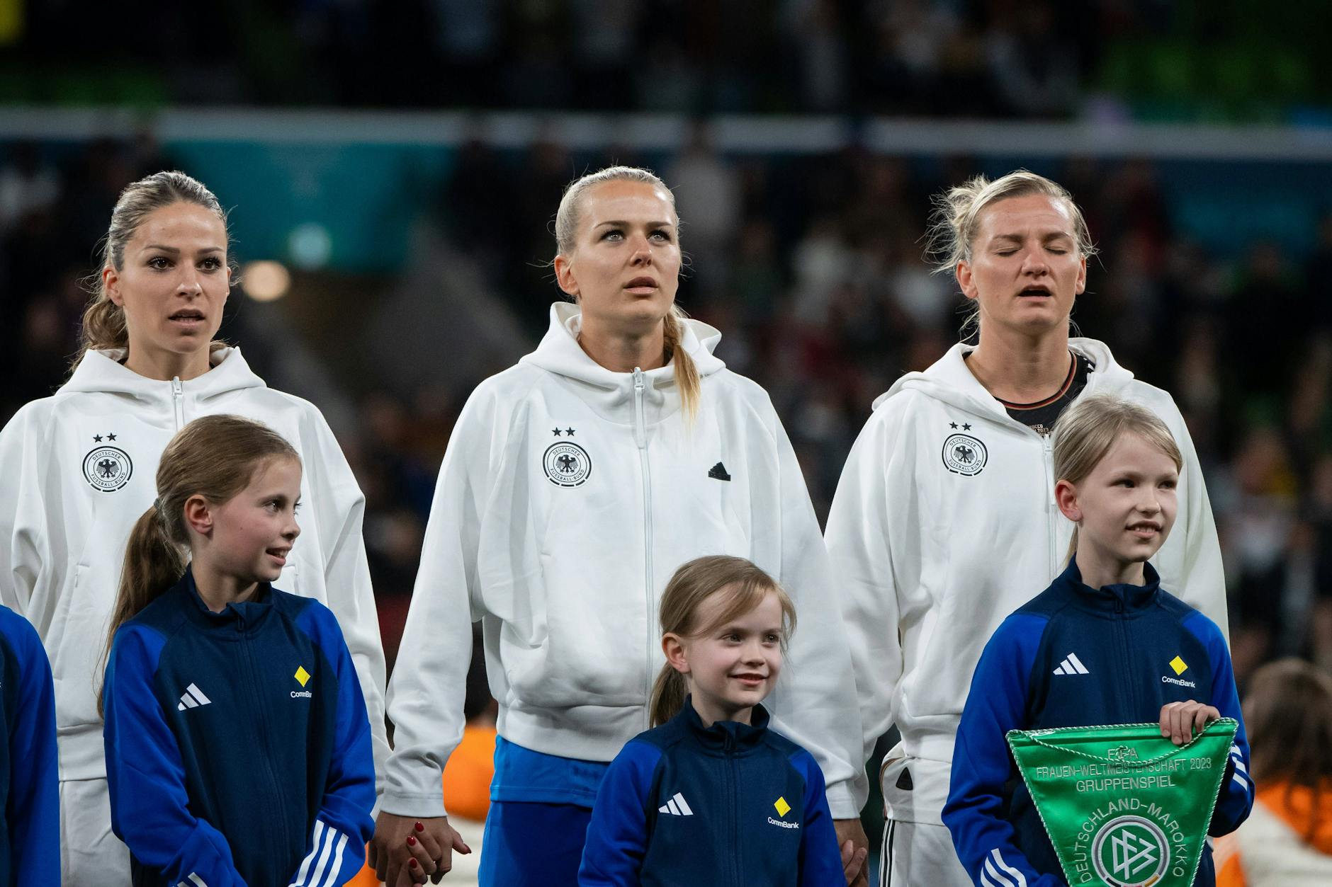 Immer dieses Vaterland! Melanie Leupolz, Merle Frohms und Alexandra Popp (v.l.) beim Singen der deutschen Nationalhymne vor dem ersten Gruppenspiel der WM gegen Marokko.