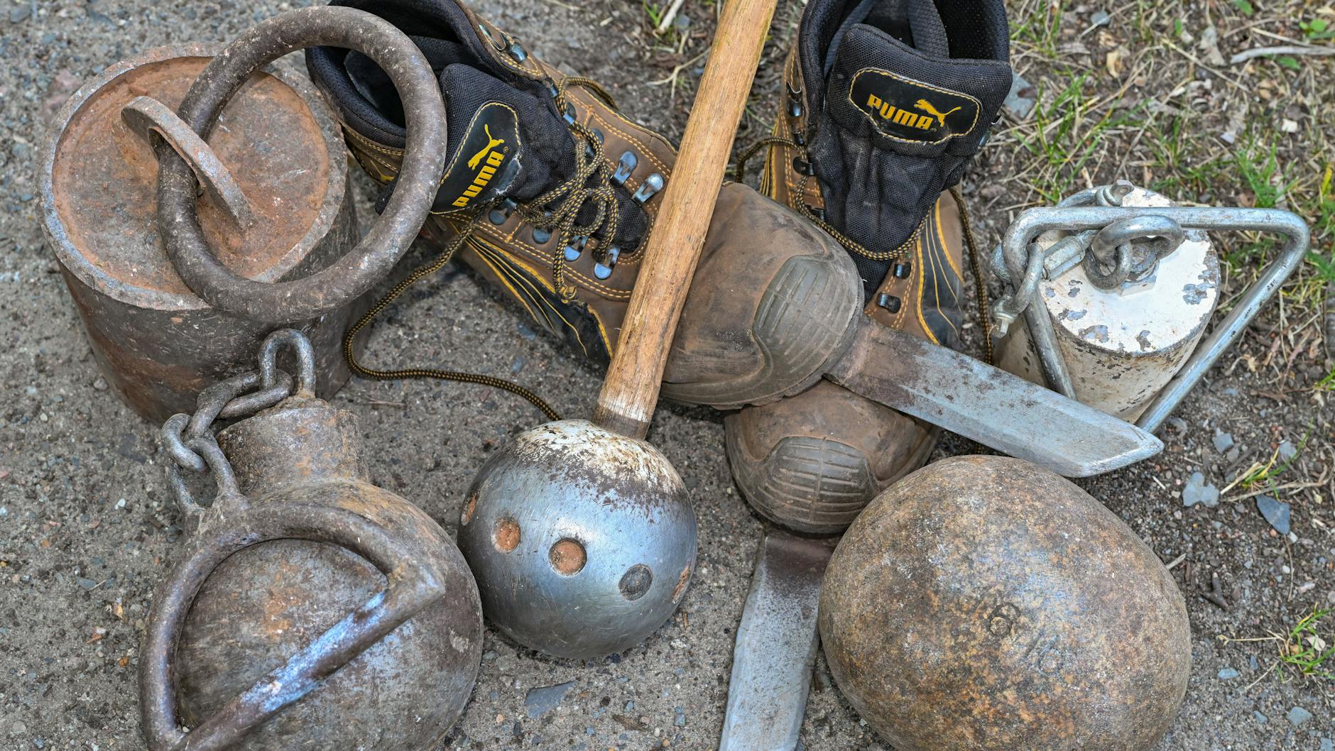 Spezielle Schuhe zum besseren Halt beim Werfen von Gewichten sowie verschiedene Wurfgeräte wie Stein und Kugelhammer vom Stone Walker Hans-Dieter Dorow, liegen auf dem Trainingsplatz.